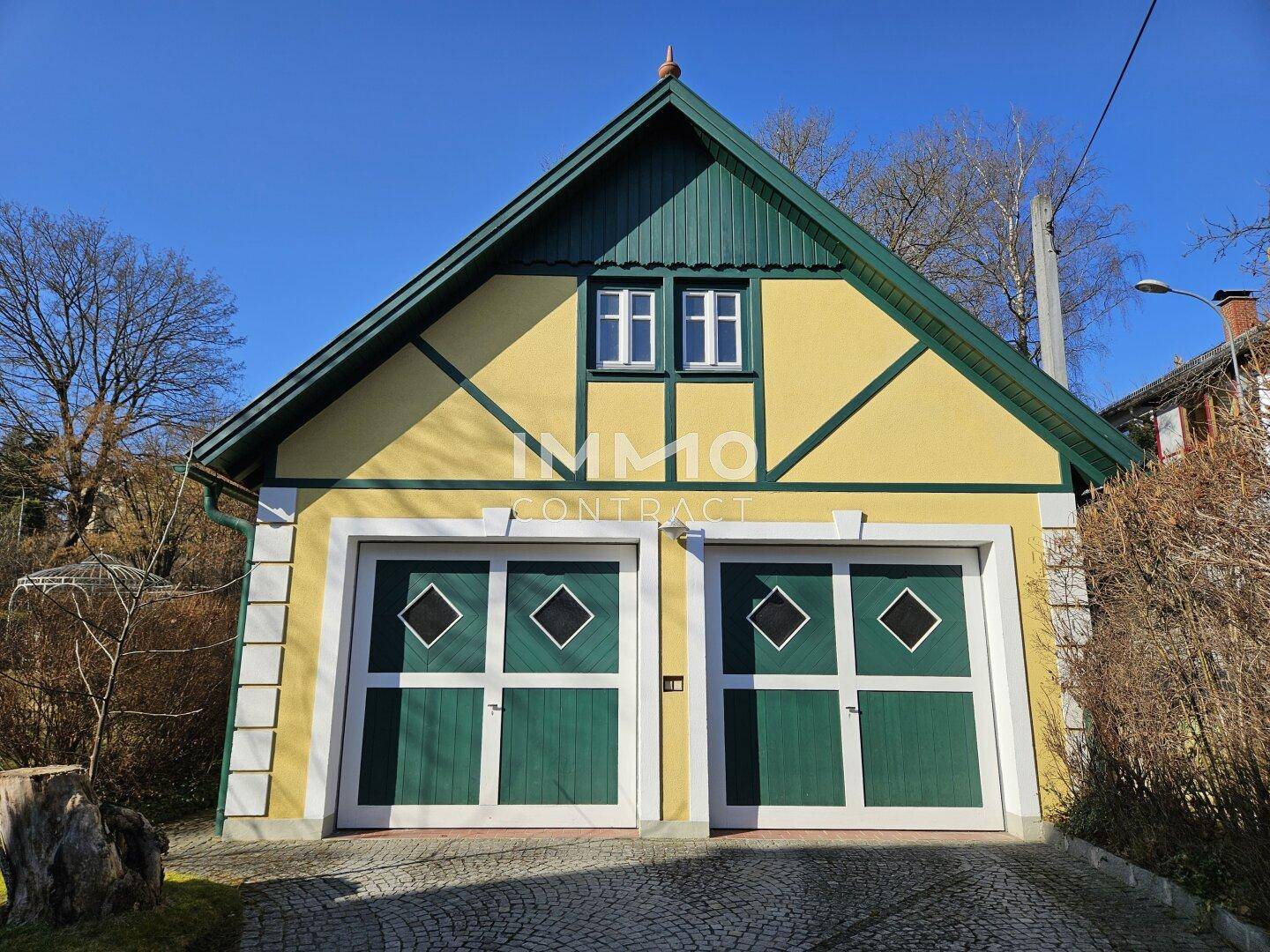 Doppelgarage mit grünen Toren und gelber Fassade, passend zum Haupthaus.