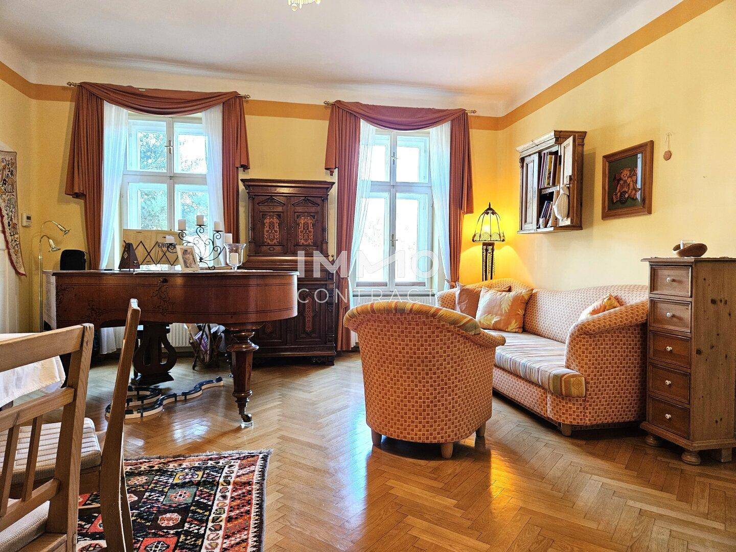 Elegantes Wohnzimmer mit Fischgrätparkett, antiken Möbeln und einem Flügel.