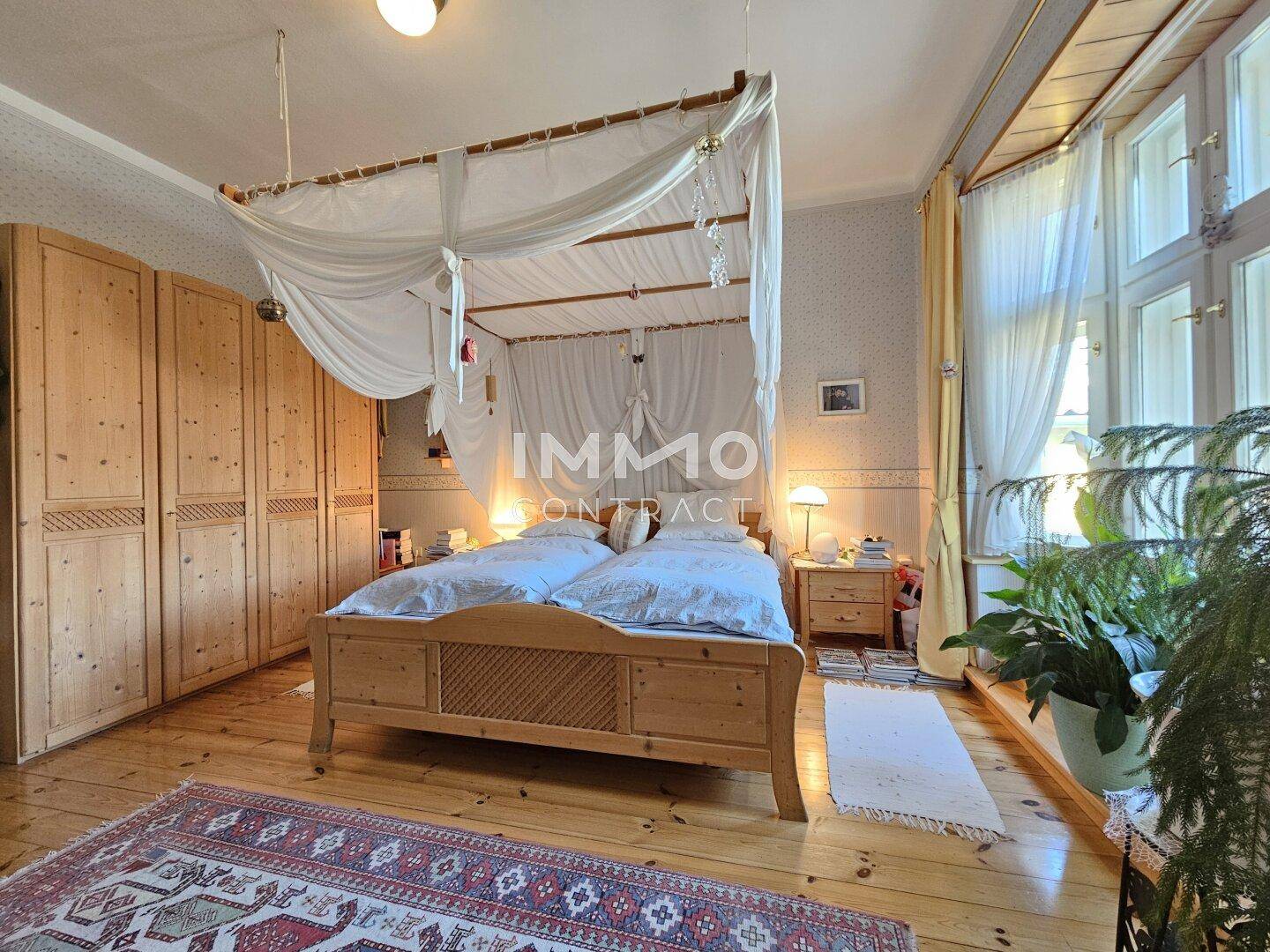 Gemütliches Schlafzimmer mit Holzschränken, Himmelbett und Blick ins Grüne.