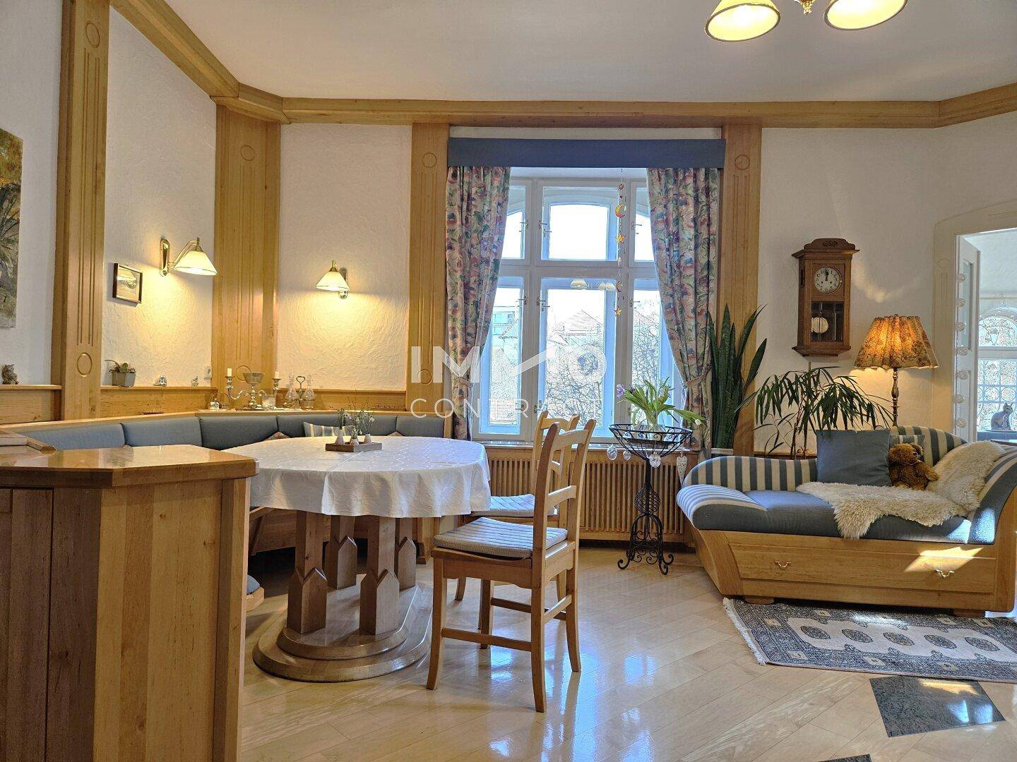 Geräumiger Wohnbereich mit Holzelementen, bequemer Chaiselongue und viel Tageslicht.