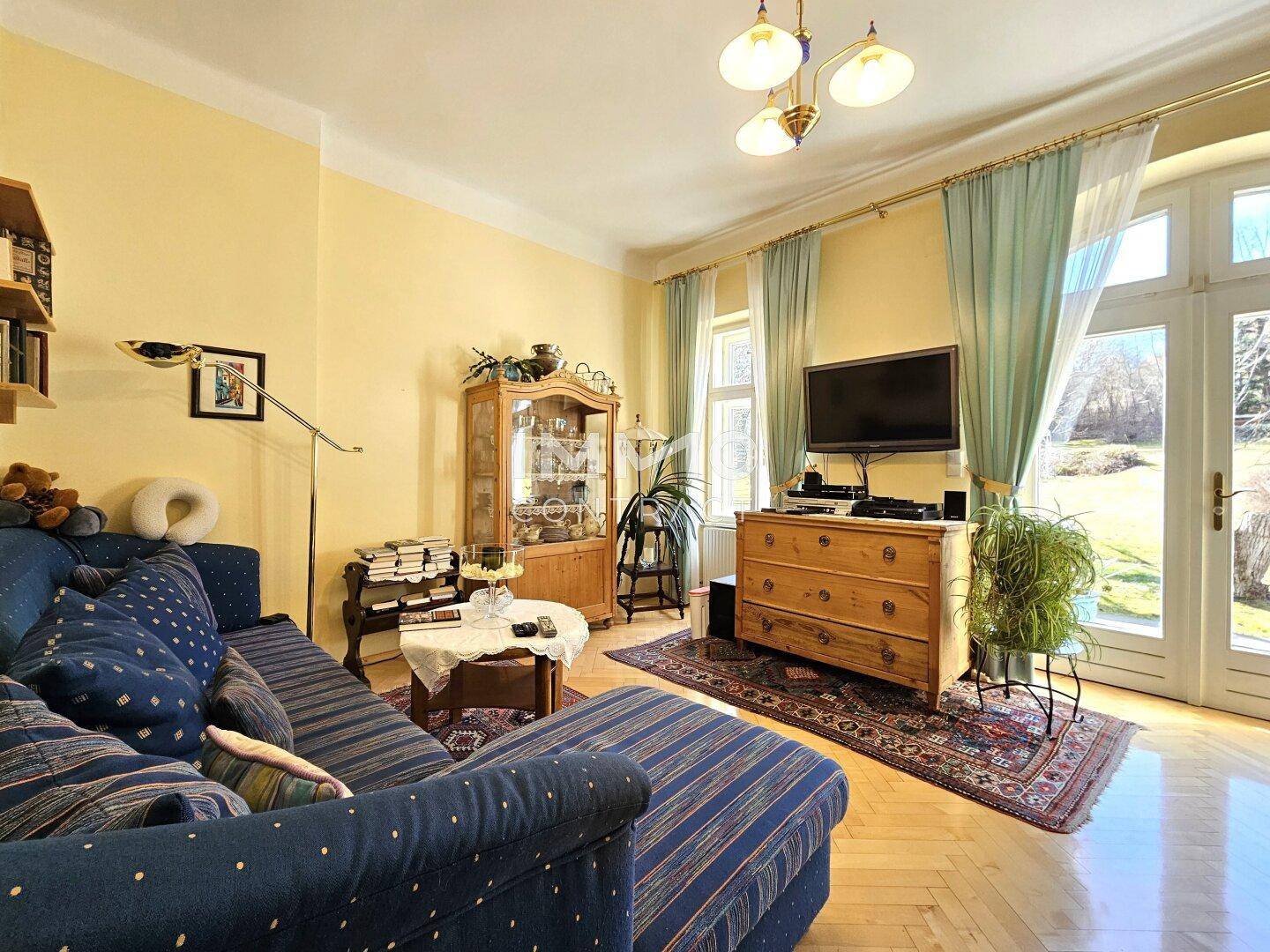 Helles Wohnzimmer mit Parkettboden, blauem Sofa und Zugang zum Garten.