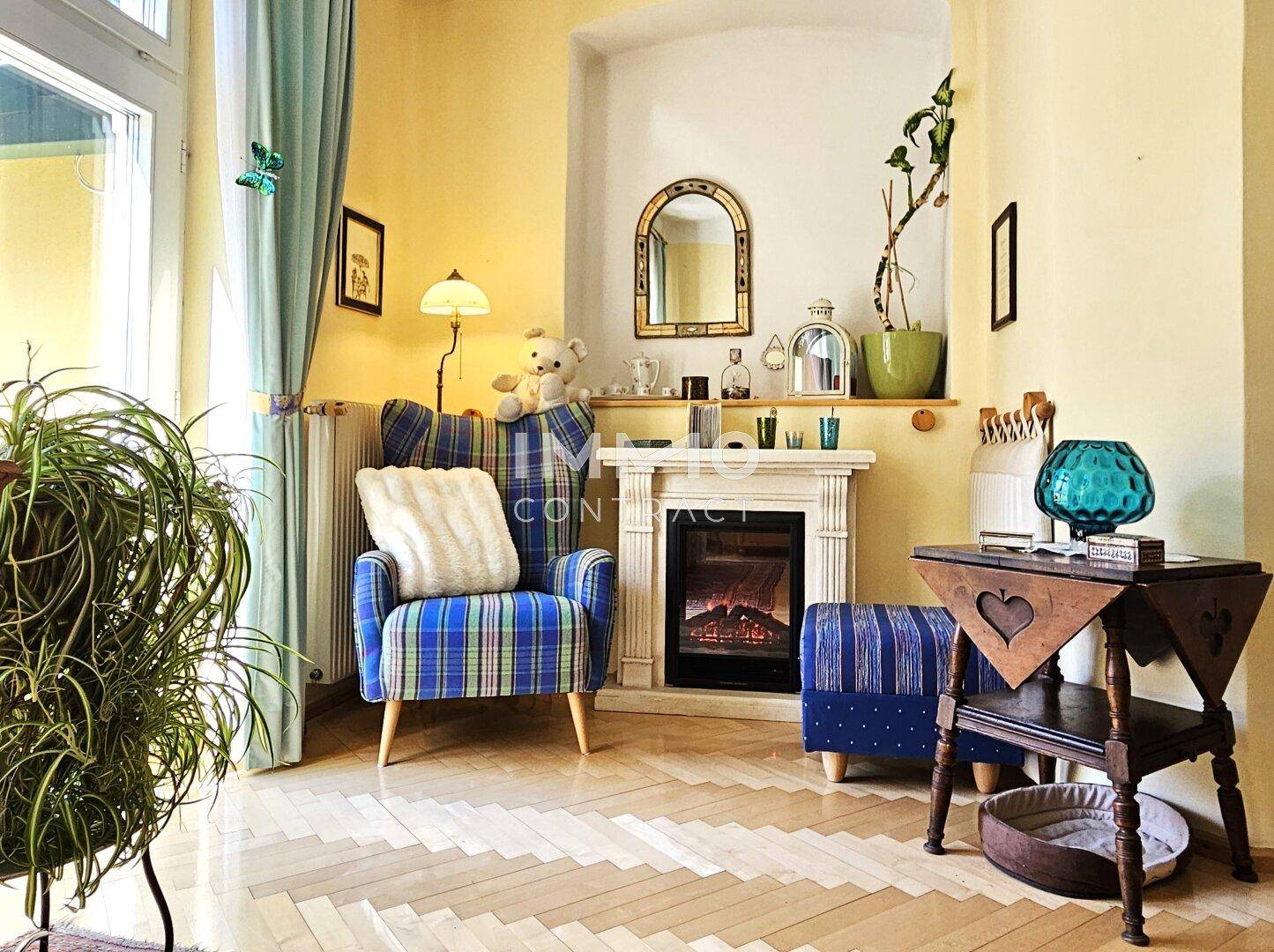 Gemütliche Sitzecke mit Kamin, Sessel und dekorativem Spiegel.
