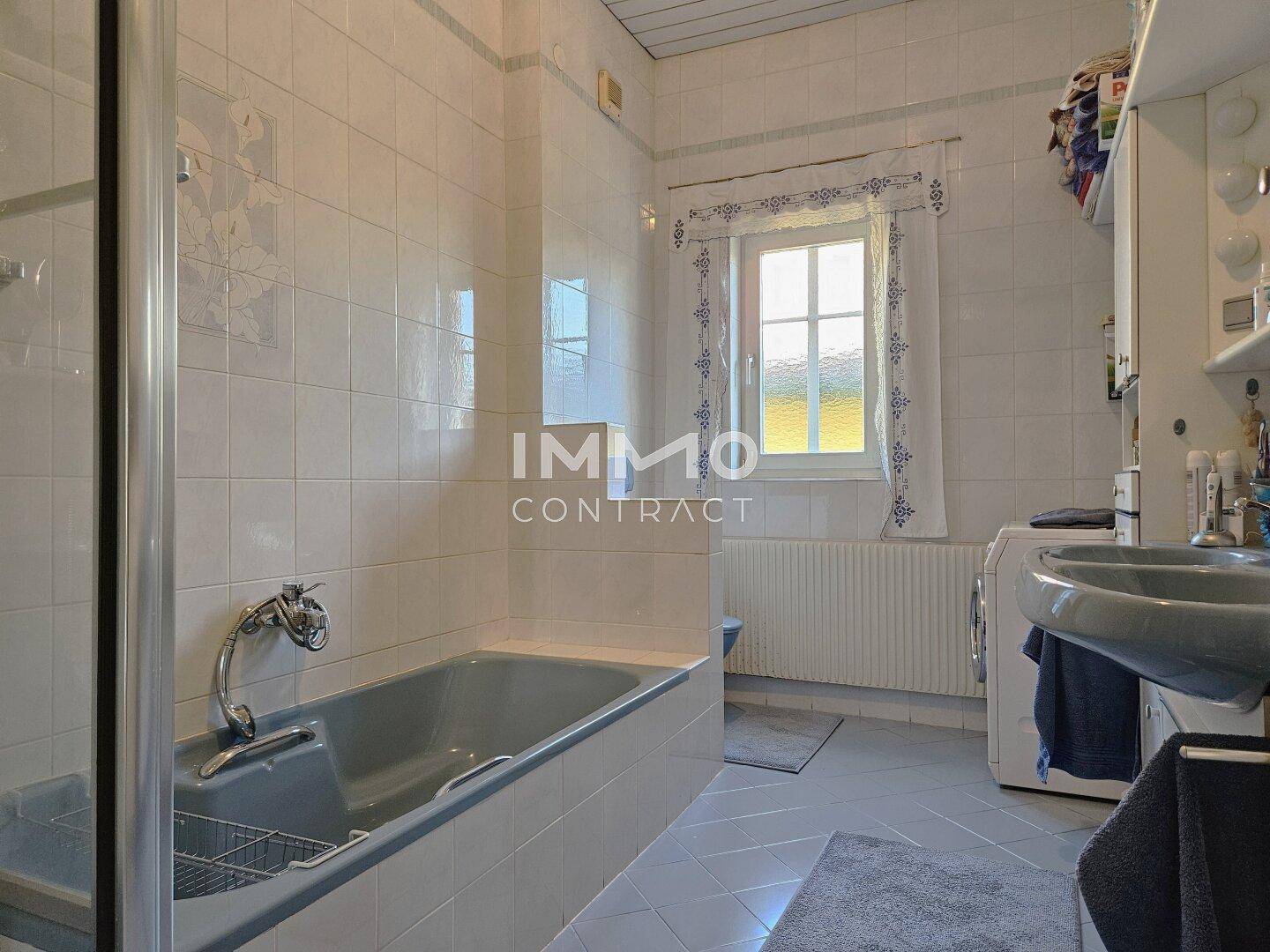 Badezimmer mit Badewanne, Dusche, Waschbecken und Fenster.