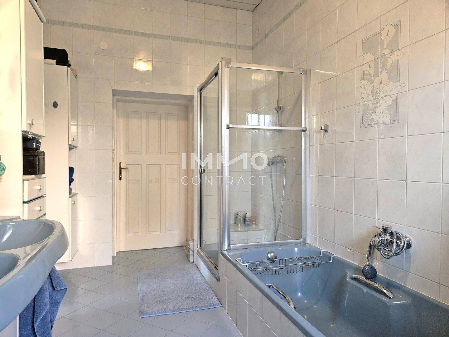 Badezimmer mit Badewanne, Duschkabine und weiß gefliesten Wänden.