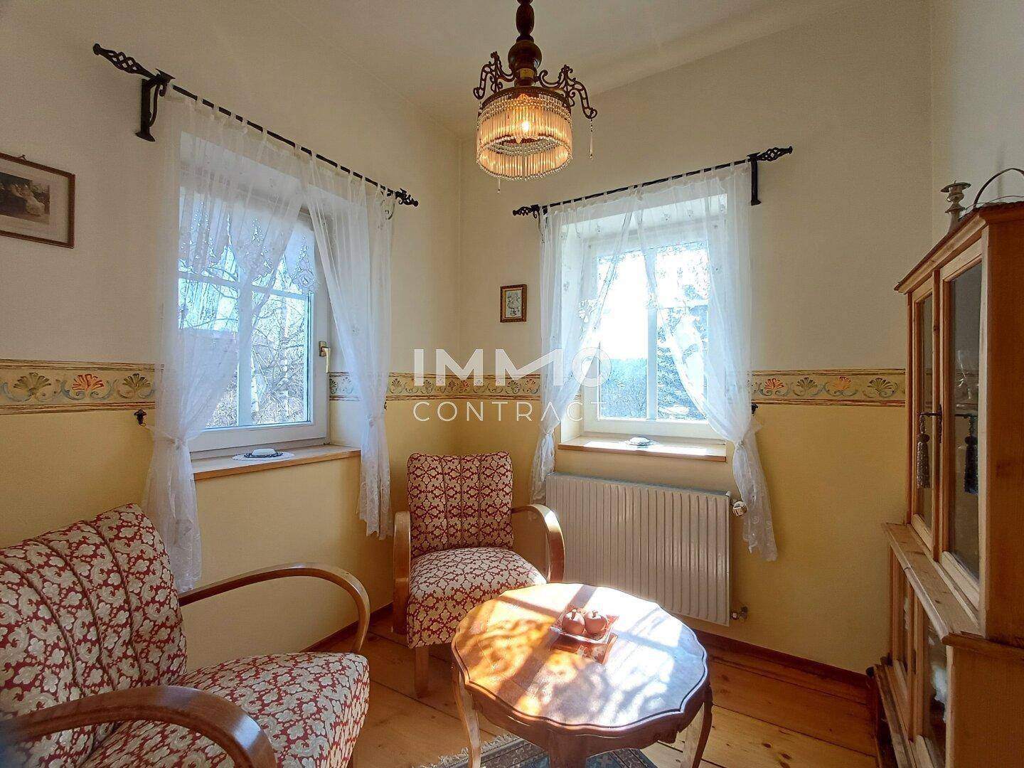 Kleines Arbeitszimmer mit zwei Sesseln, Holztisch und Fenster.