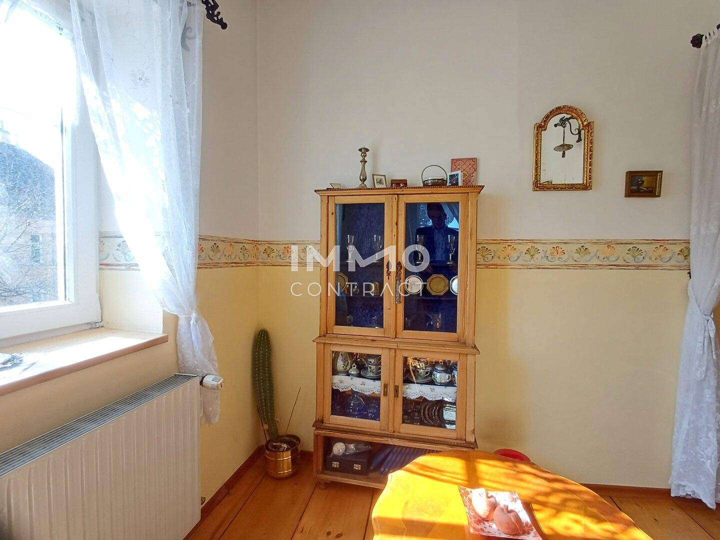 Gemütliches Arbeitszimmer mit Holzschrank, Fenster und viel Tageslicht.