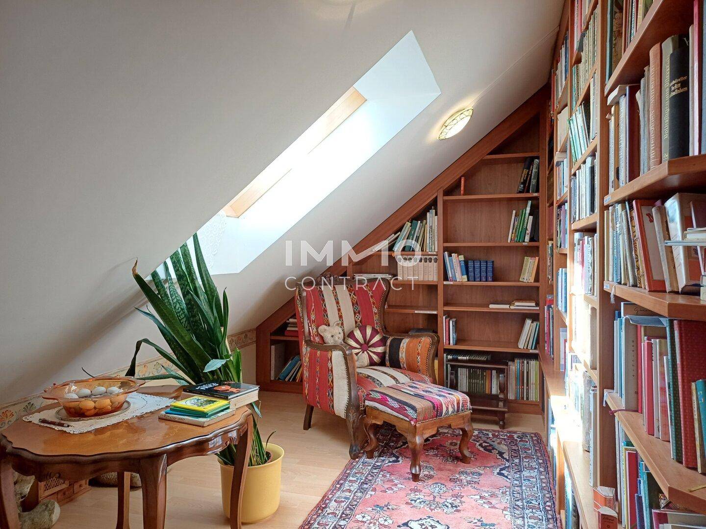 Dachgeschoss-Bibliothek mit Bücherregalen, Lesesessel und Dachfenster.