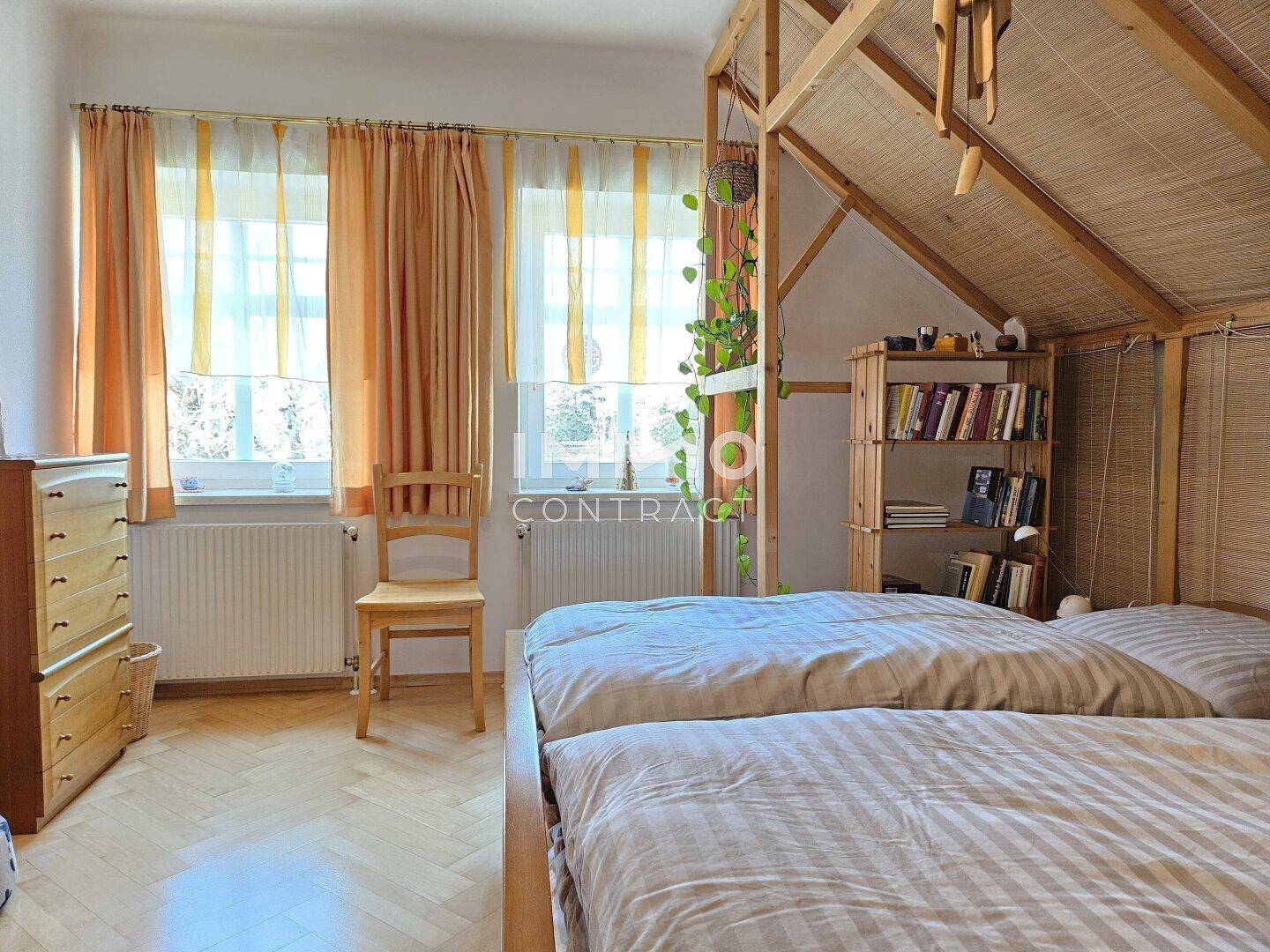 Helles Schlafzimmer mit zwei Betten, Holzmöbeln und Fenster.