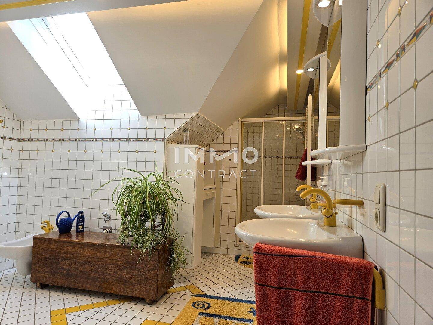 Badezimmer im Dachgeschoss mit Doppelwaschbecken, Dusche und Dachfenster.