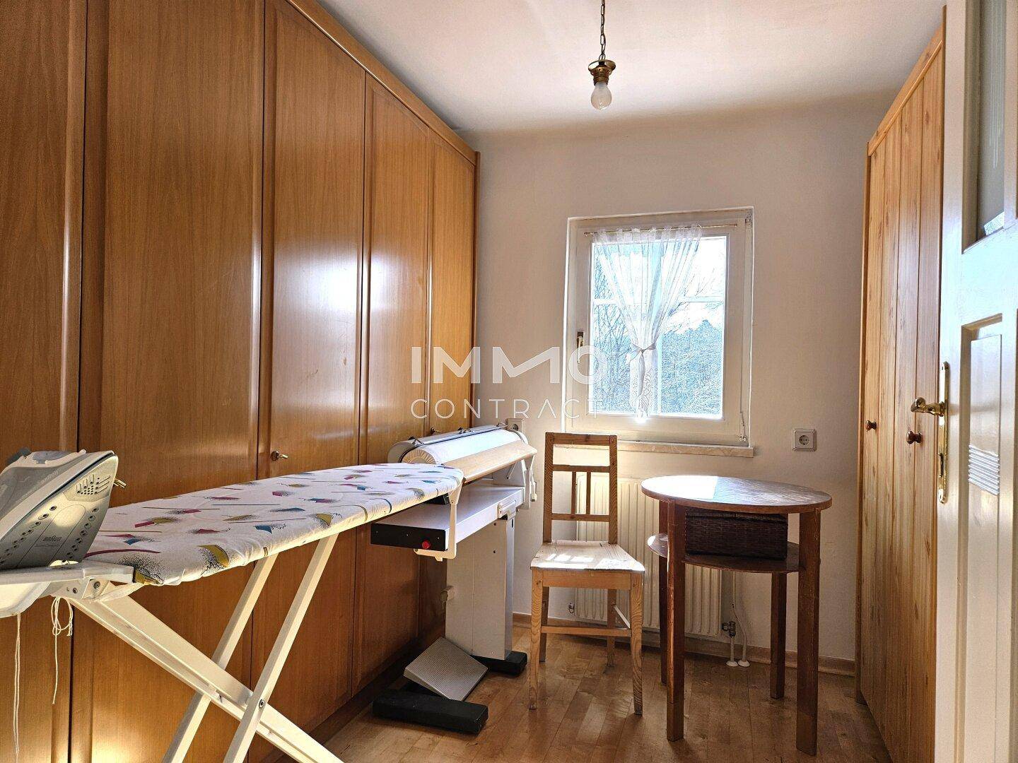 Praktischer Hauswirtschaftsraum mit Einbauschränken und Fenster.