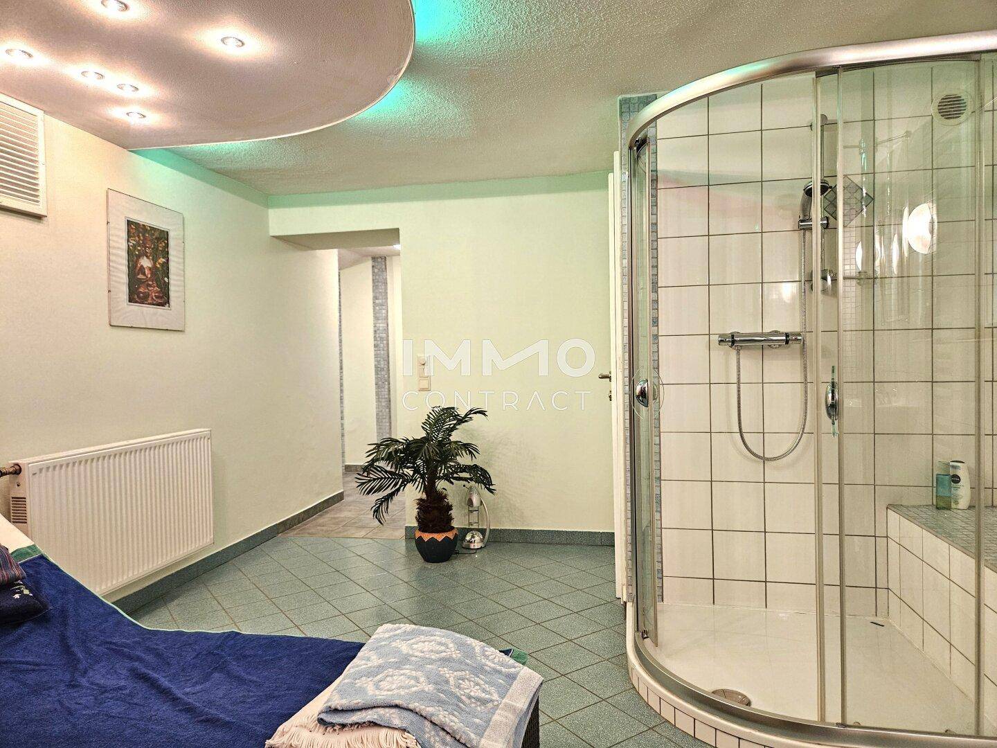 Entspannungsbereich mit Dusche, Liege und indirekter Beleuchtung.