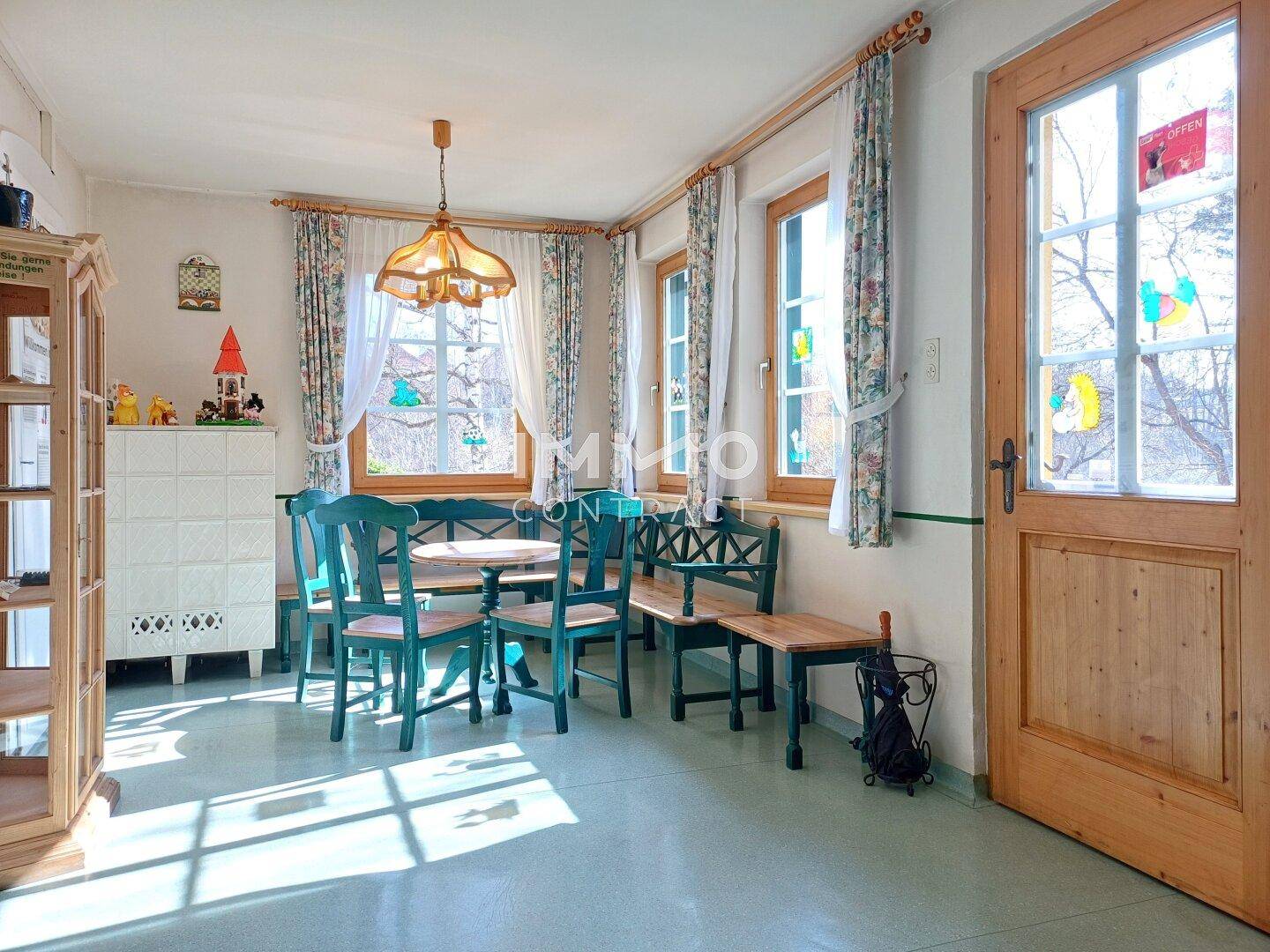 Heller Essbereich mit Holztisch, grünen Stühlen und Blick ins Grüne.