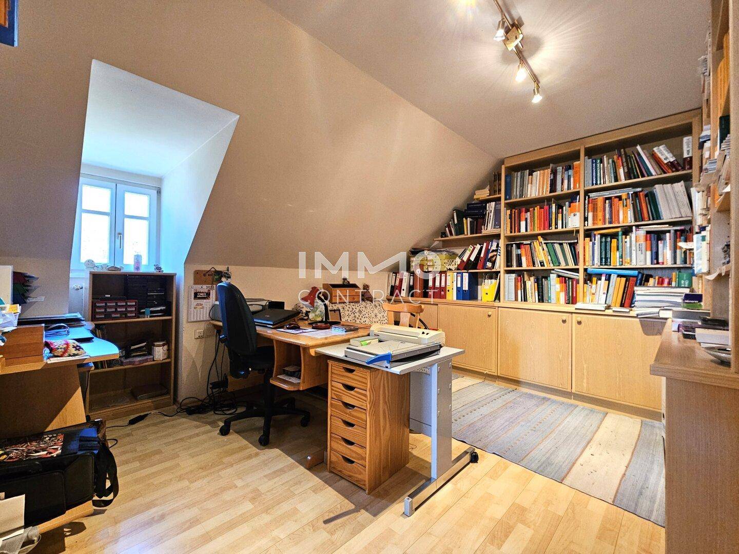 Dachgeschoss-Büro mit umfangreichen Bücherregalen und Schreibtisch.