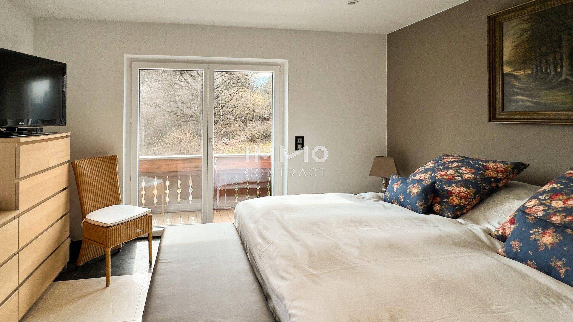 Schlafzimmer mit Doppelbett, Kommode und Zugang zu einem Balkon mit Aussicht.