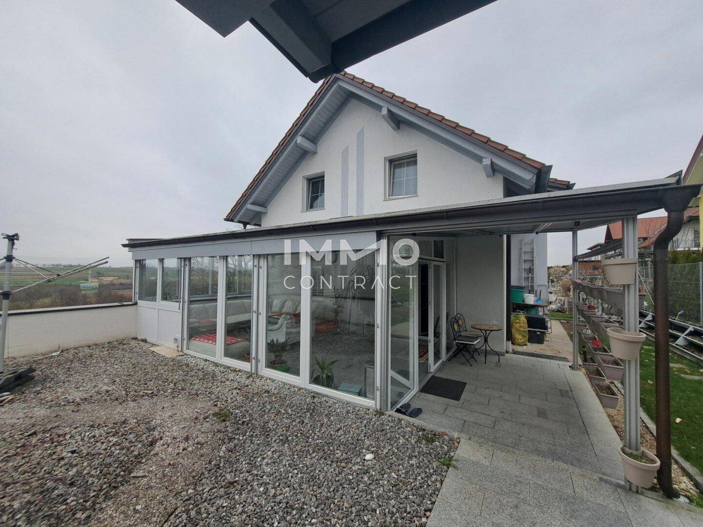 Gartenbereich mit Wintergarten und gepflastertem Sitzplatz neben dem Haus.