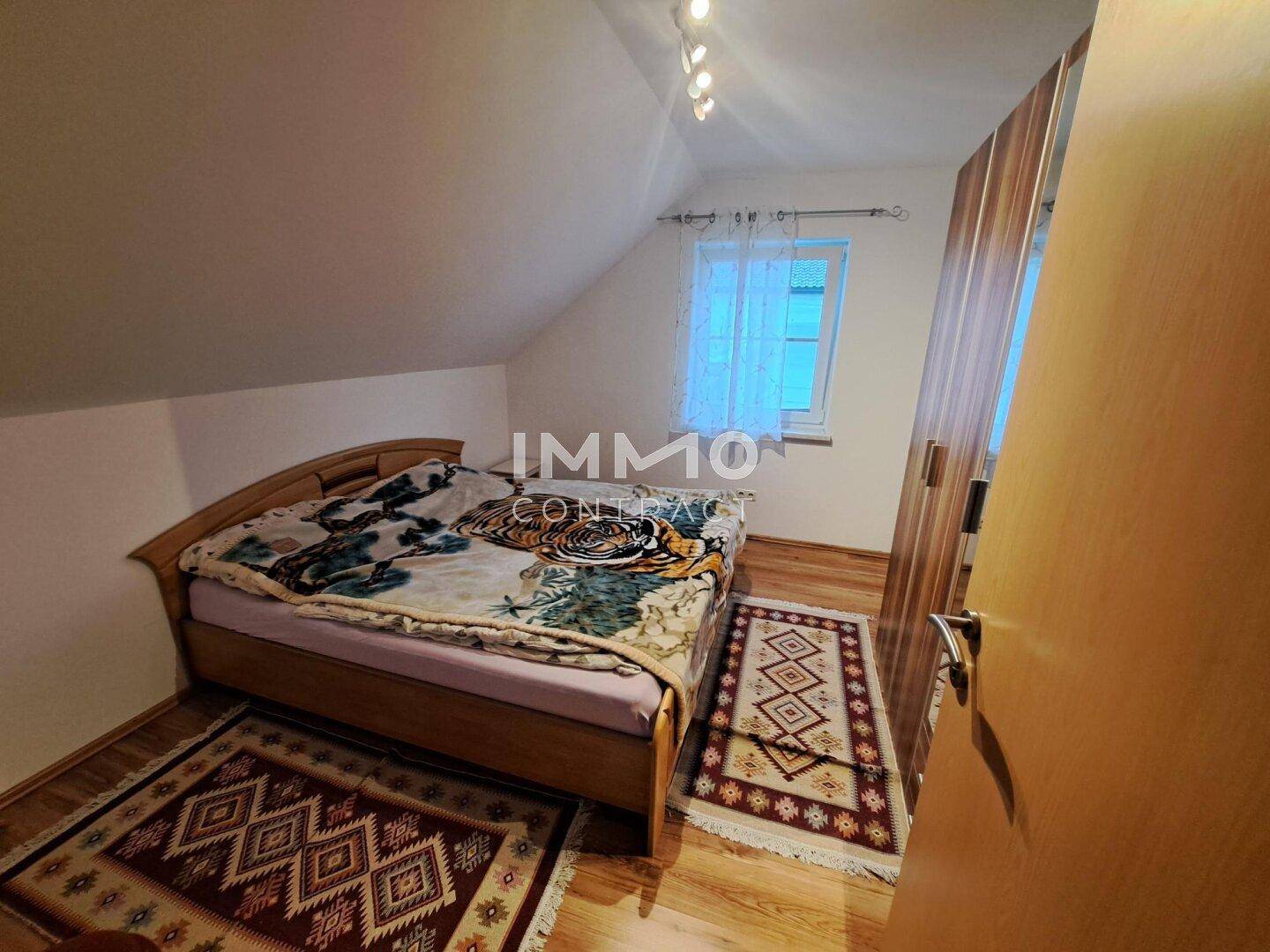 Gemütliches Schlafzimmer im Dachgeschoss mit Holzbett, Laminatboden und Dachschräge.
