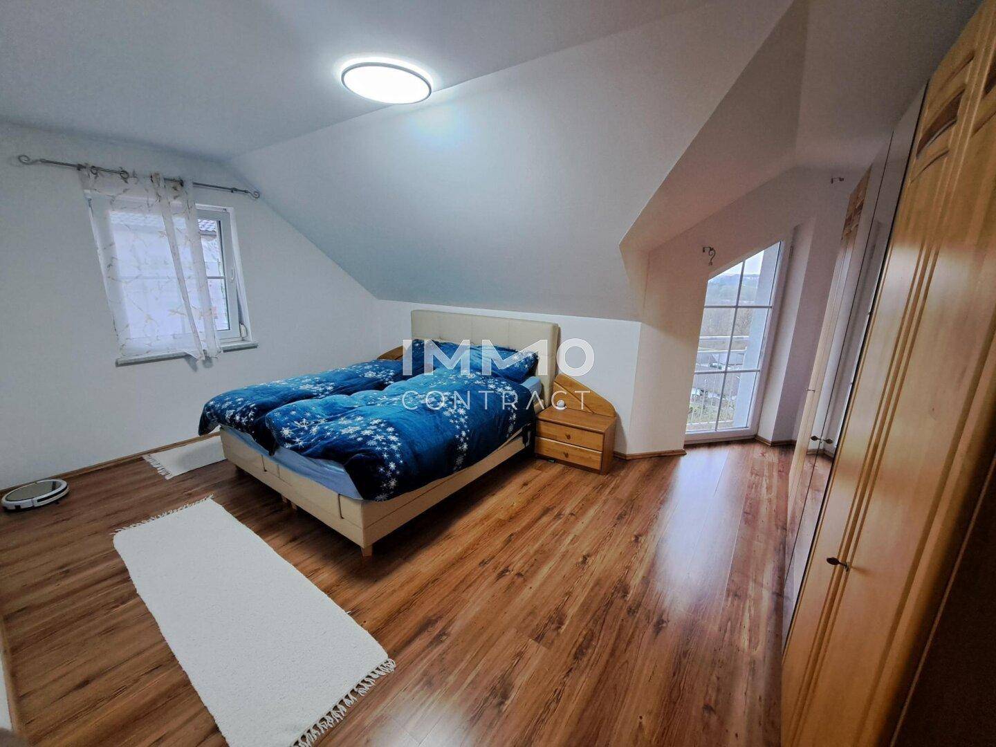 Helles Schlafzimmer im Dachgeschoss mit zwei Einzelbetten, Laminatboden und Dachschräge.