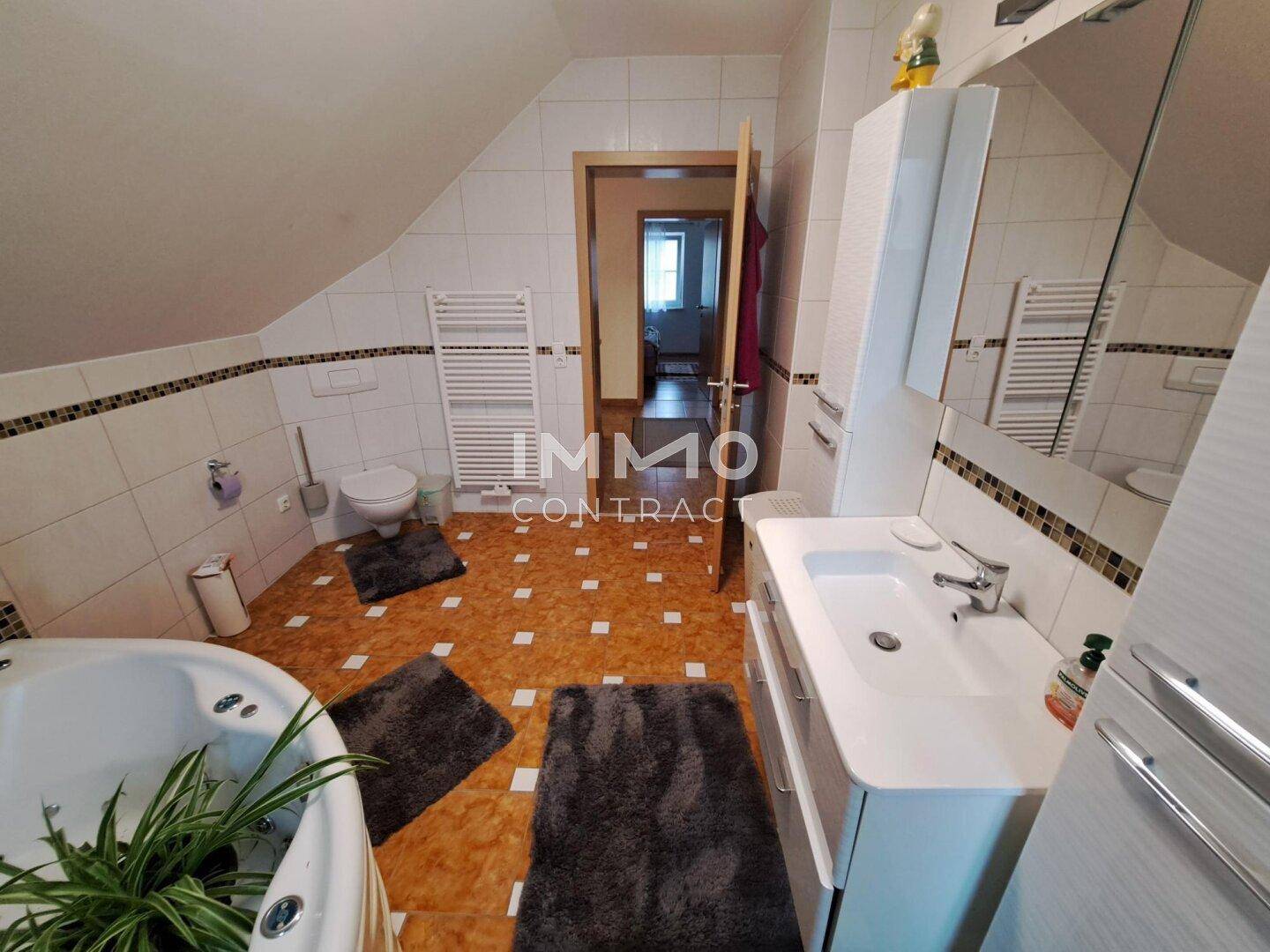 Dachgeschoss-Badezimmer mit Eckbadewanne, Einzelwaschbecken und Handtuchheizkörper.