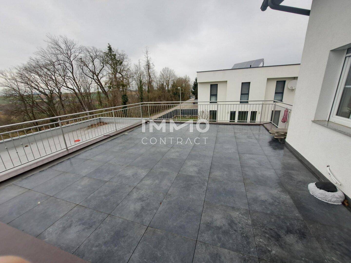 Weitläufige Dachterrasse mit dunklen Fliesen und weitem Blick in die Umgebung.