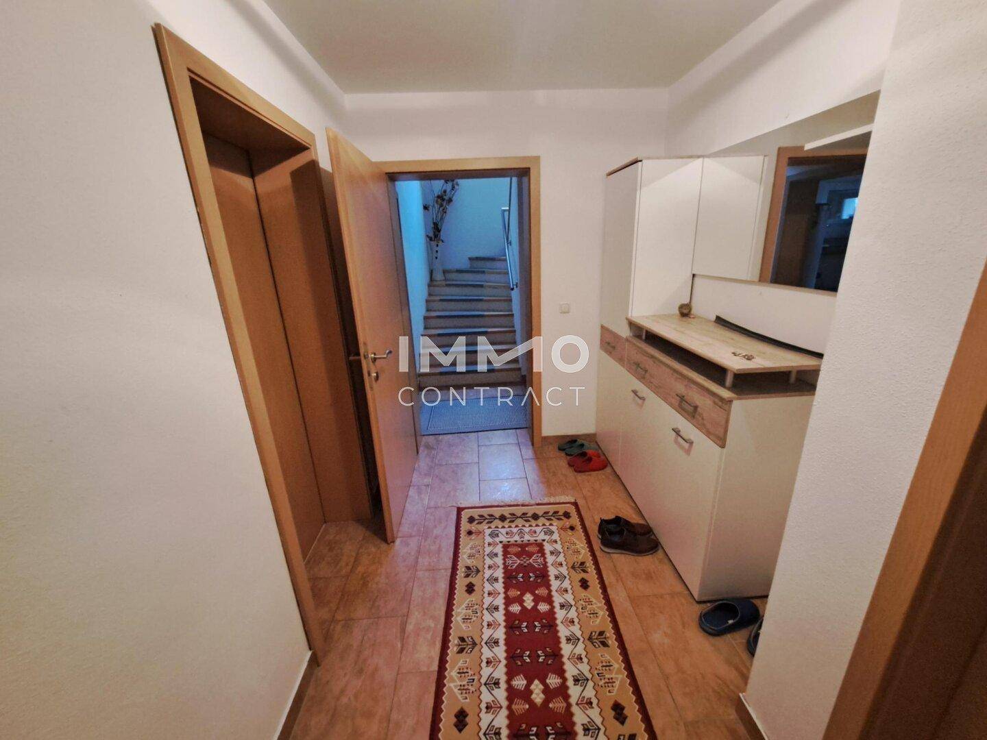 Eingangsbereich mit Fliesenboden, Garderobe und Zugang zur Treppe.