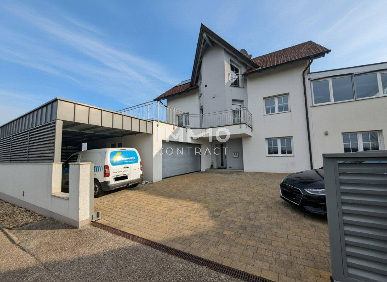 Vorderansicht des Hauses mit gepflasterter Einfahrt, Carport und Garage.