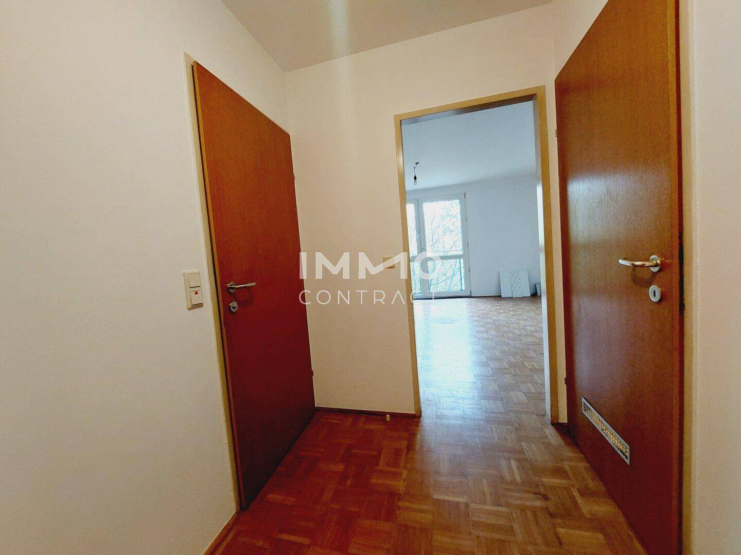 Flur mit Parkettboden und Holztüren, der zu verschiedenen Räumen führt.