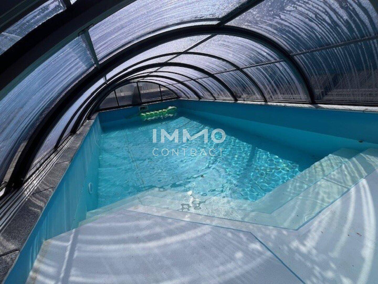 Überdachter Swimmingpool mit klarem Wasser und breiten Stufen, ideal für Schwimmvergnügen bei jedem Wetter.