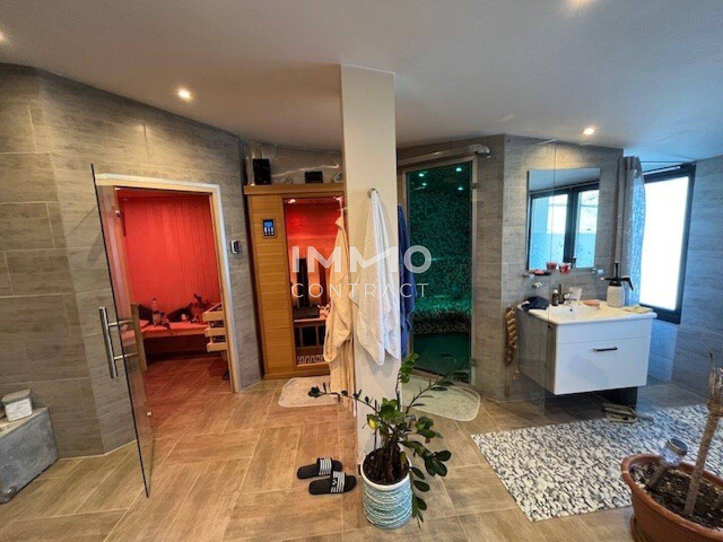 Luxuriöser Wellnessbereich mit Sauna, Dampfdusche und modernem Waschbecken in entspannender Atmosphäre.