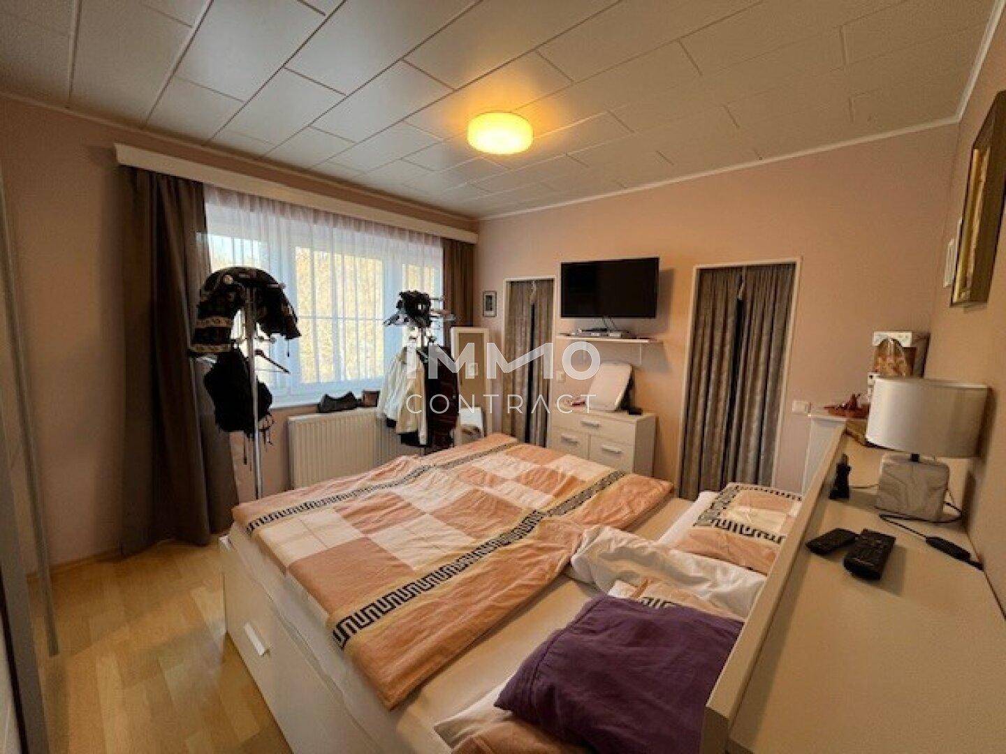 Gemütliches Schlafzimmer mit Holzboden, großem Bett und integrierten Schränken für Stauraum.