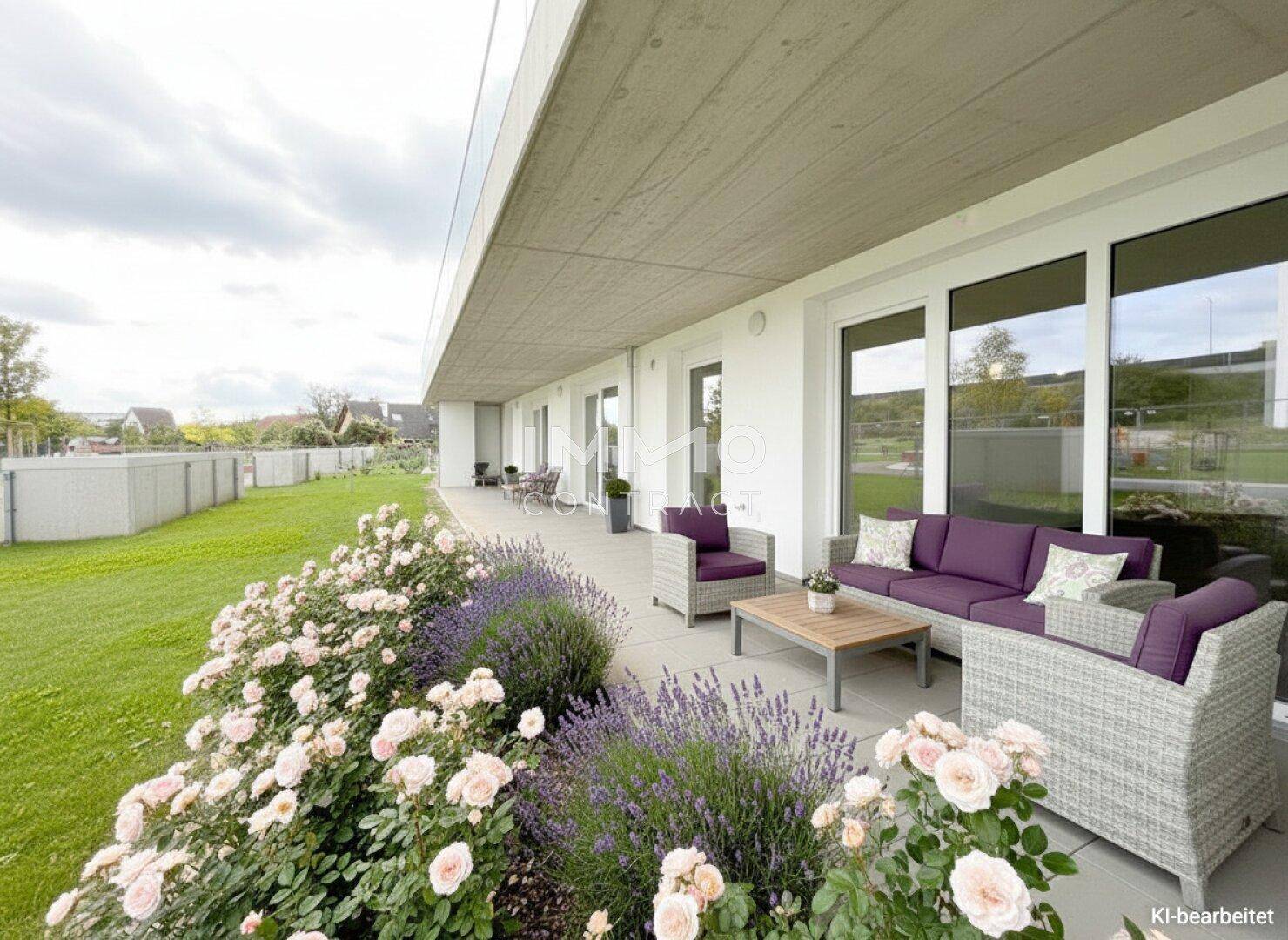 Geräumige Terrasse mit bequemen Loungemöbeln und gepflegten Blumenbeeten vor dem Gebäude.