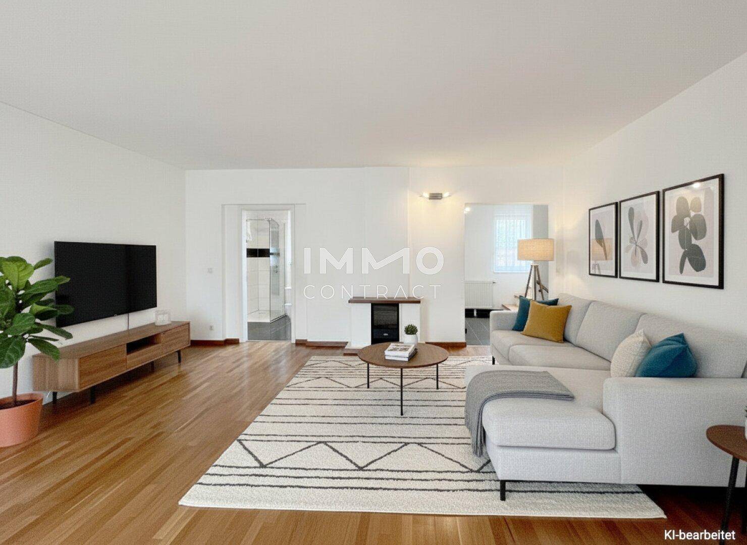 Modern eingerichtetes Wohnzimmer mit Holzboden, bequemer Couch und Blick in einen angrenzenden Raum.