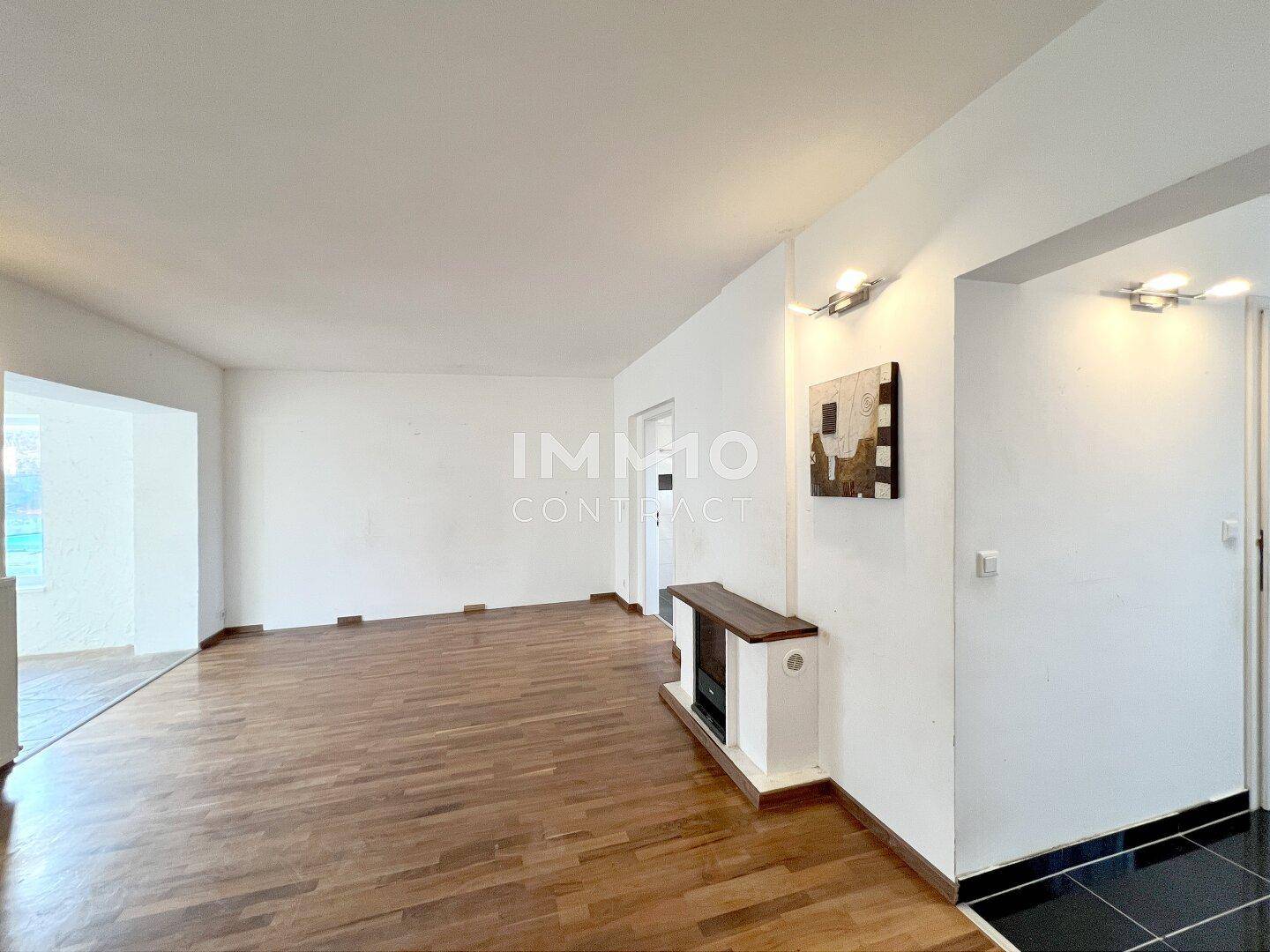 Helles Wohnzimmer mit Holzboden und weiß gestrichenen Wänden, bereit für individuelle Einrichtungsideen.