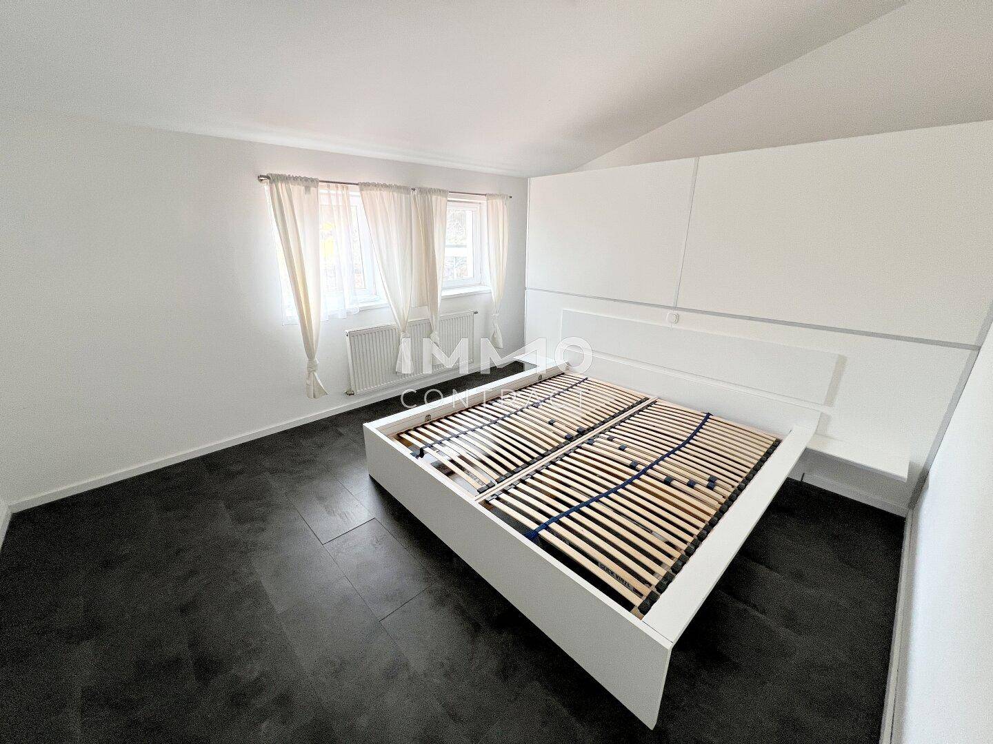 Geräumiges Schlafzimmer mit dunklem Boden und weiß gestrichenen Wänden, bereit zur individuellen Gestaltung.