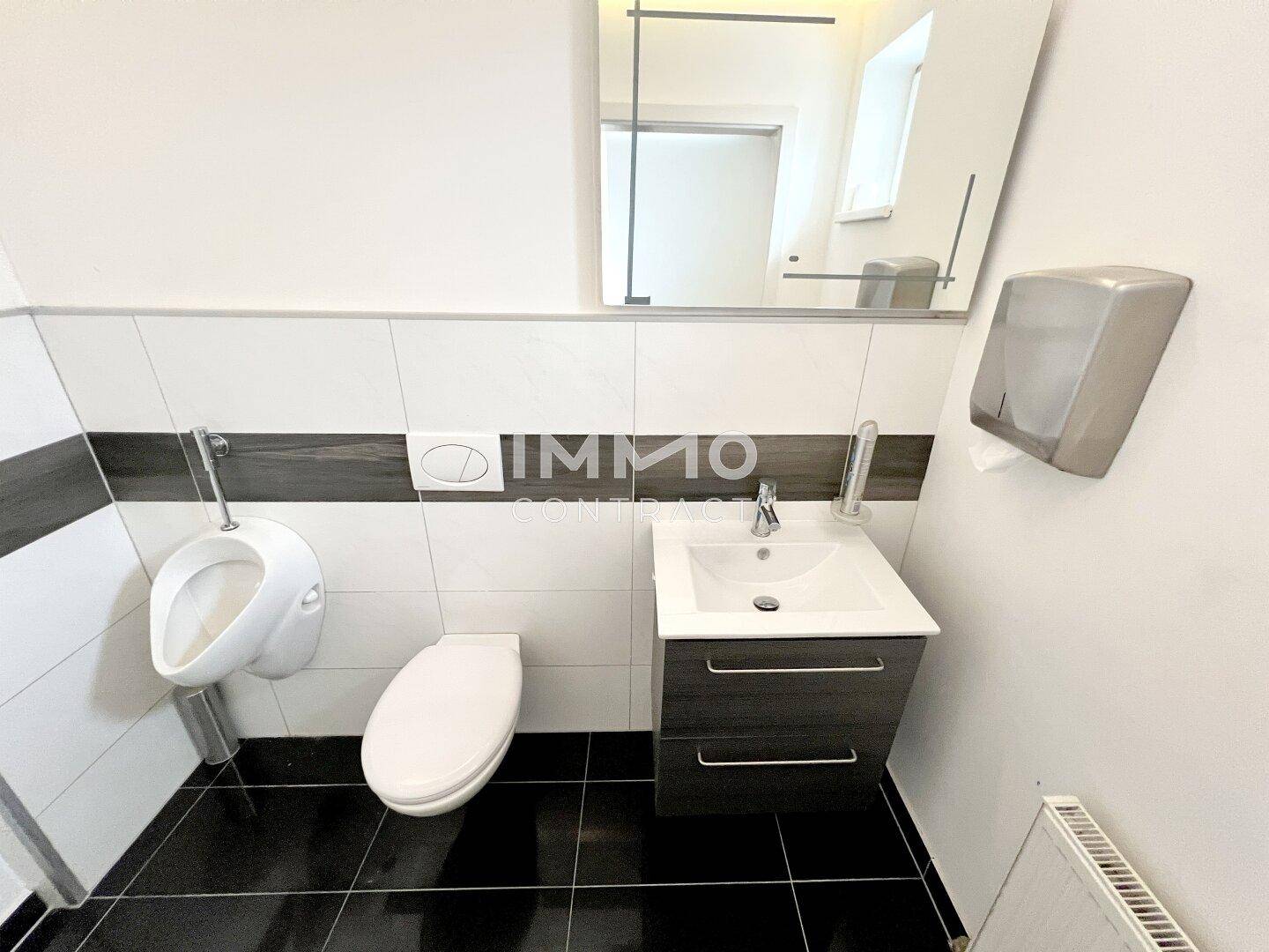 Modernes Gäste-WC mit Urinal, Toilette und Waschbecken, ausgestattet mit dunklen Bodenfliesen.