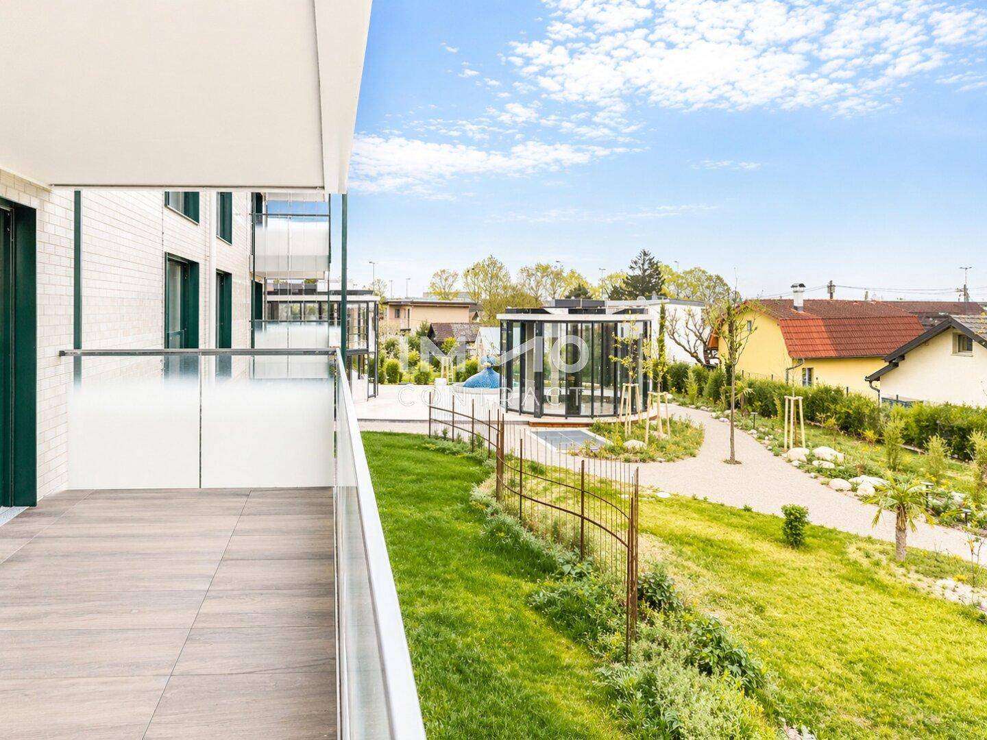 Blick von der Terrasse auf die grüne Umgebung mit einem modernen Pavillon und Wohngebäuden.