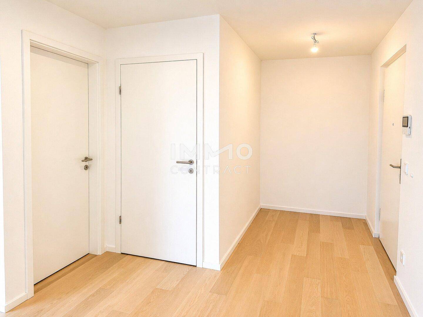 Heller Eingangsbereich mit Holzboden und weißen Türen, der zu den Wohnräumen führt.