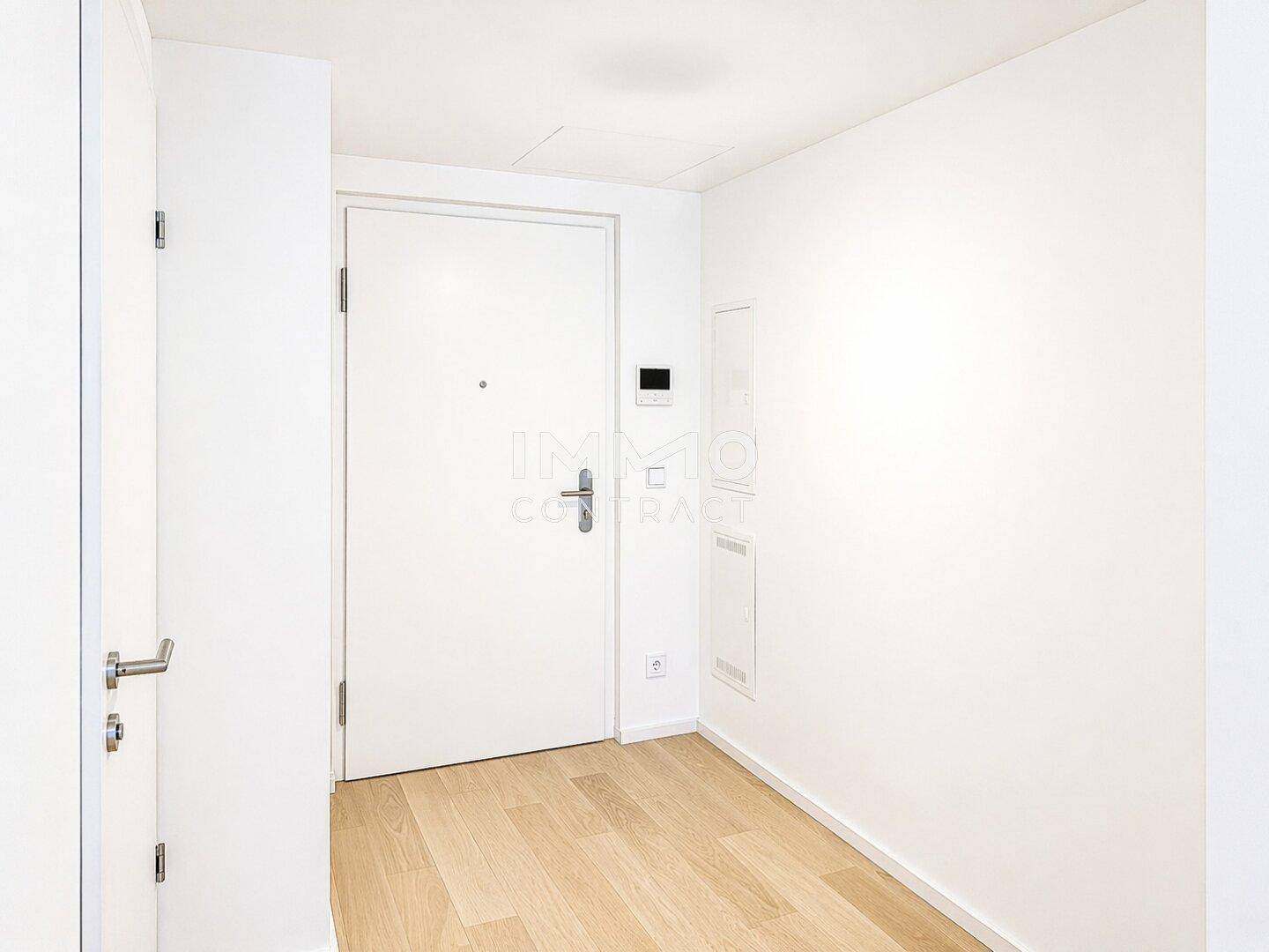 Heller Eingangsbereich mit Holzboden und weißer Tür, bietet direkten Zugang zur modernen Wohnung.