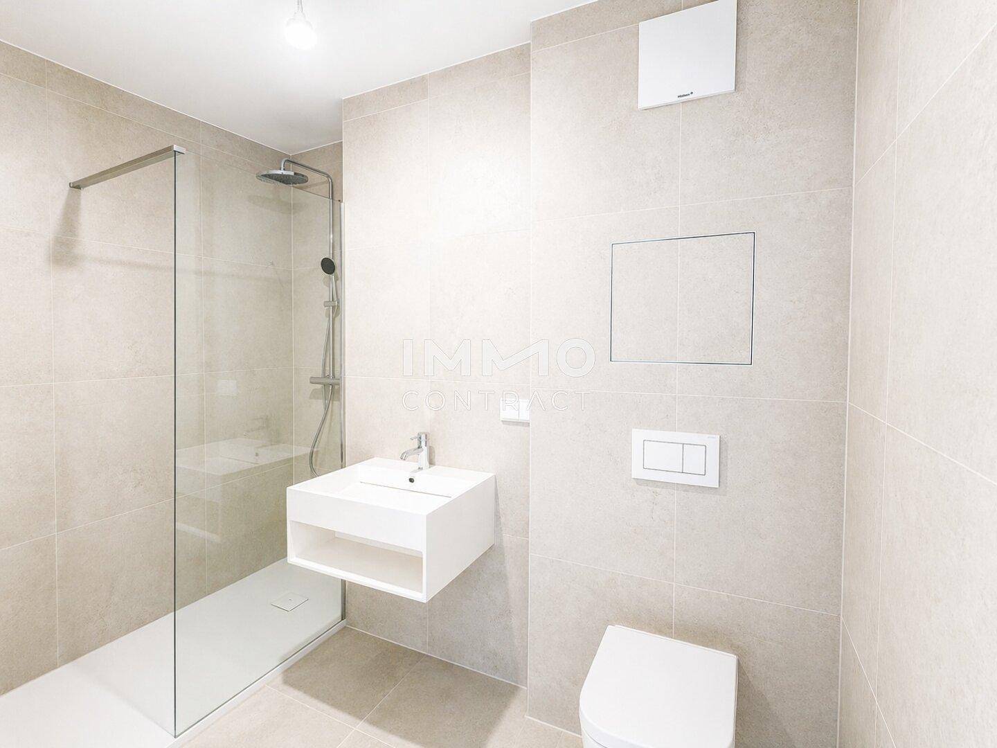 Modernes Badezimmer mit begehbarer Dusche, Wand-WC und schwebendem Waschtisch in hellen Fliesen.