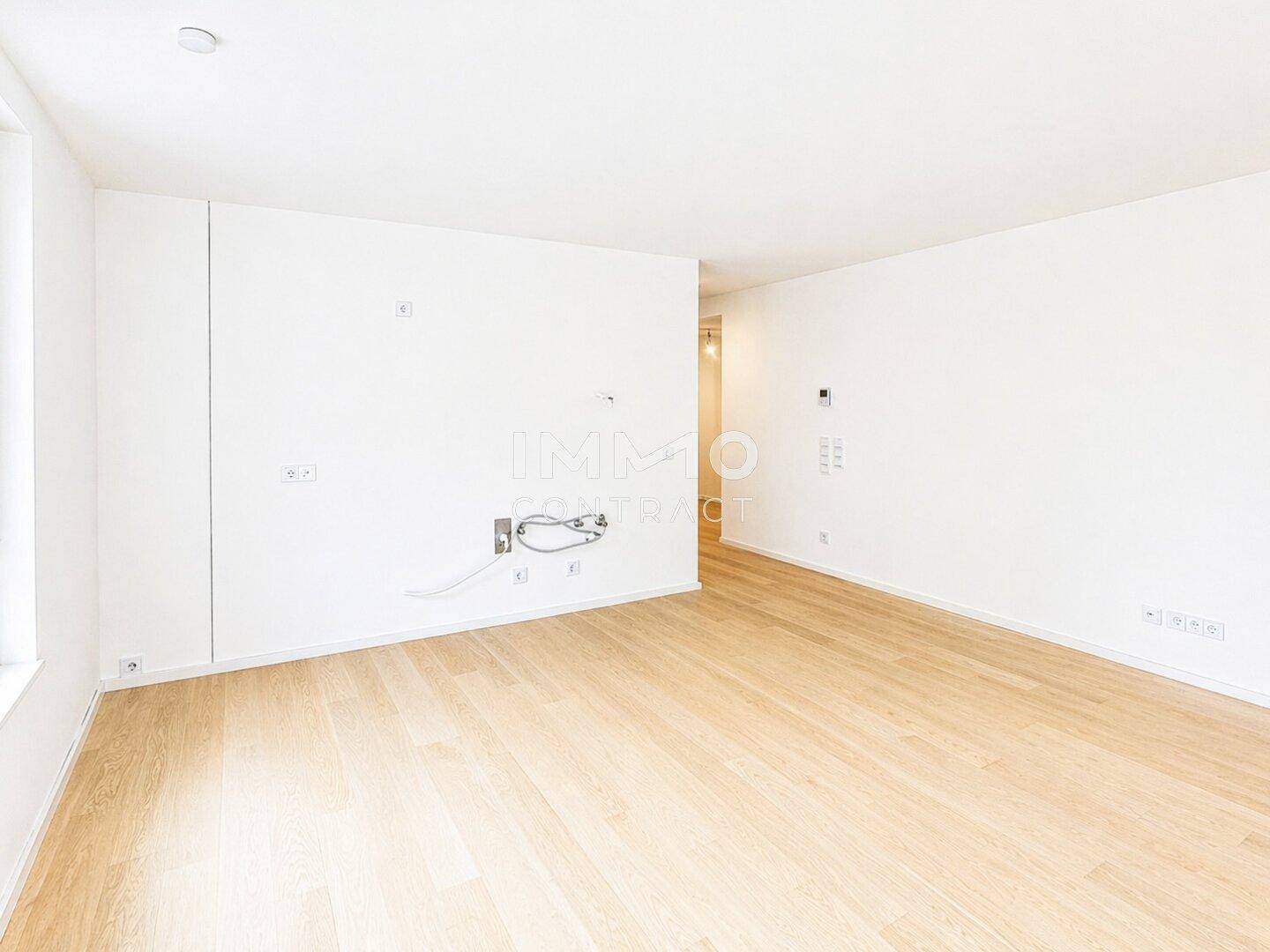 Heller, leerer Raum mit Holzboden und vorbereiteten Anschlüssen an der Wand für Medien.