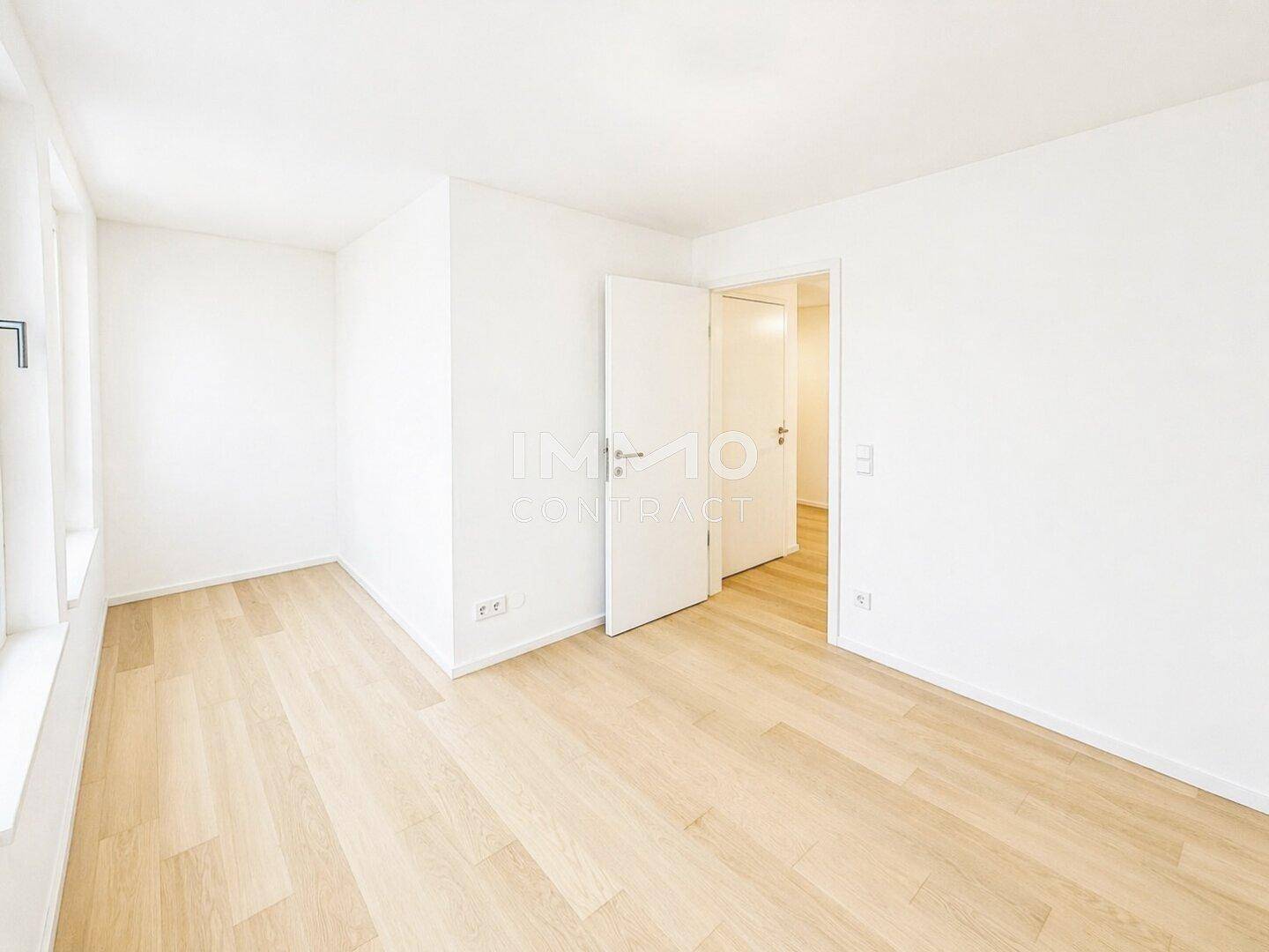 Leeres Schlafzimmer mit hellem Holzboden und weiß gestrichenen Wänden, bereit zum Einrichten.
