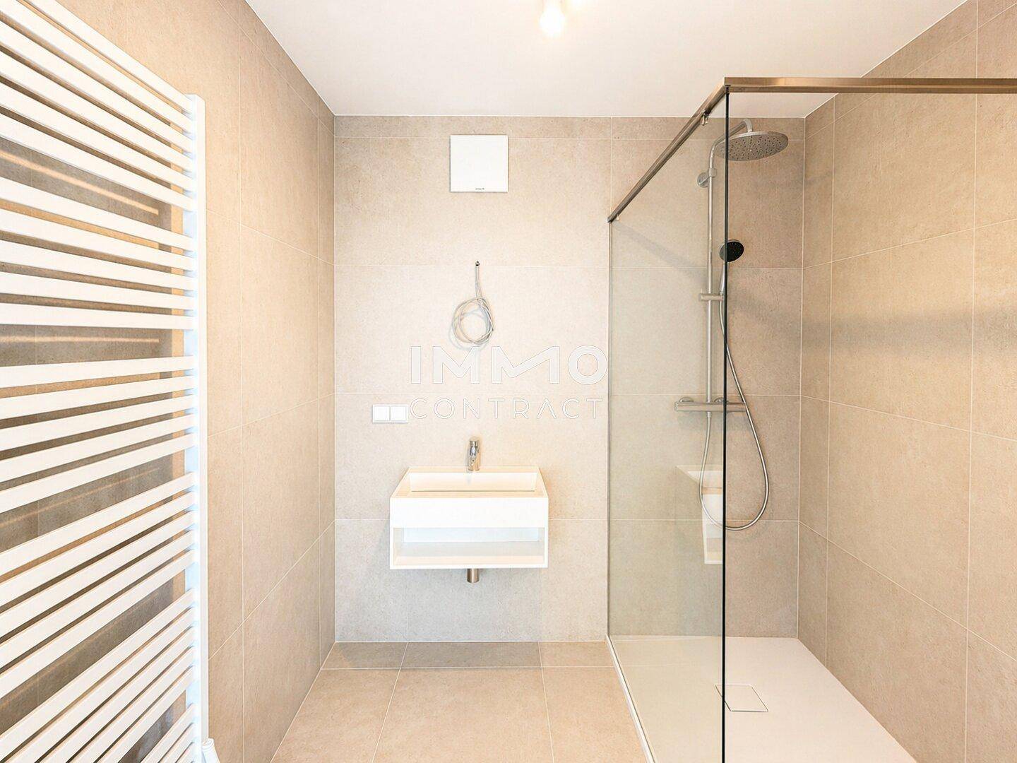 Modernes Badezimmer mit beigefarbenen Fliesen, schwebendem Waschbecken und begehbarer Dusche.