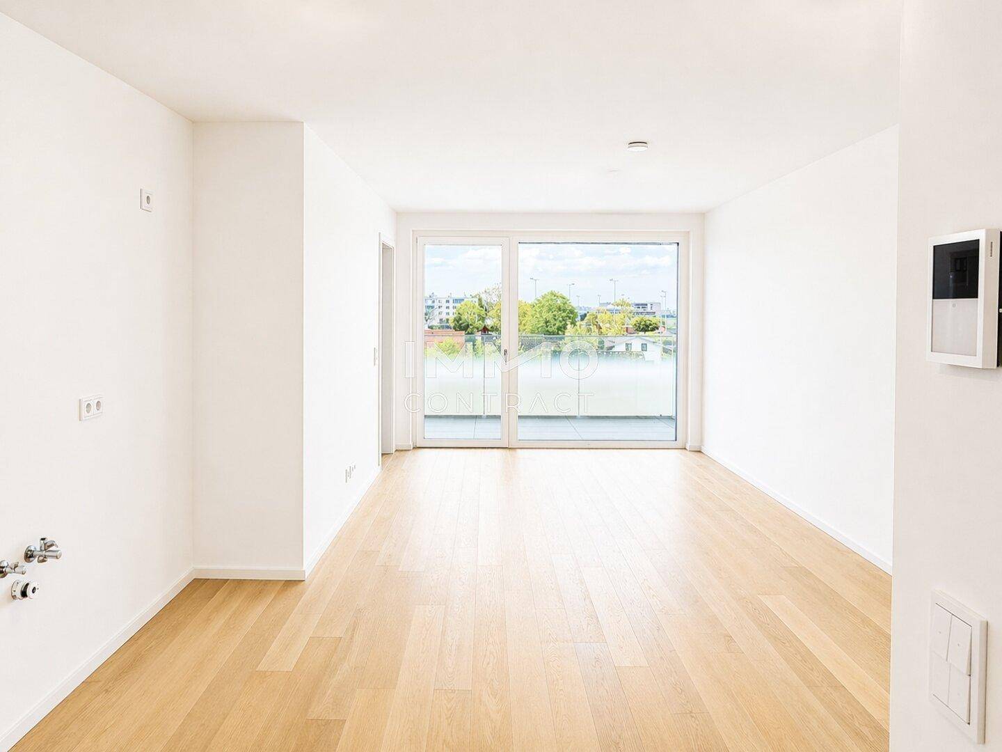 Heller, leerer Raum mit Holzboden und Zugang zu einem Balkon, ideal als Wohnbereich.