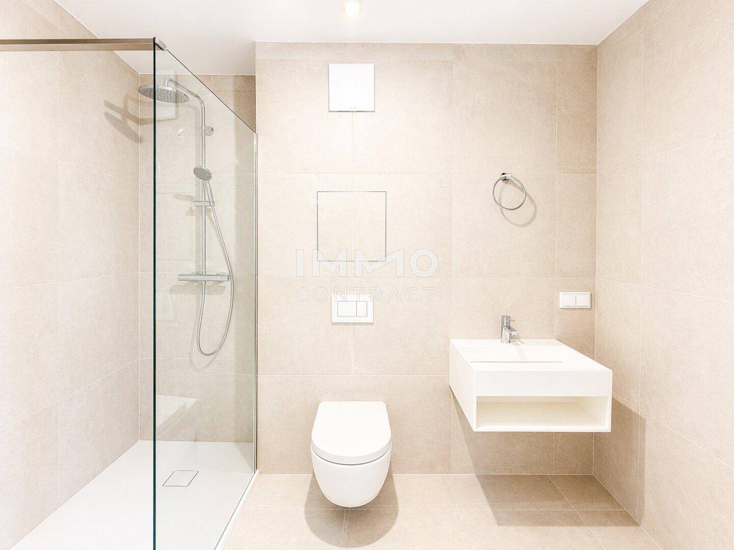 Modernes Badezimmer mit beigefarbenen Fliesen, ebenerdiger Dusche und Wand-WC.