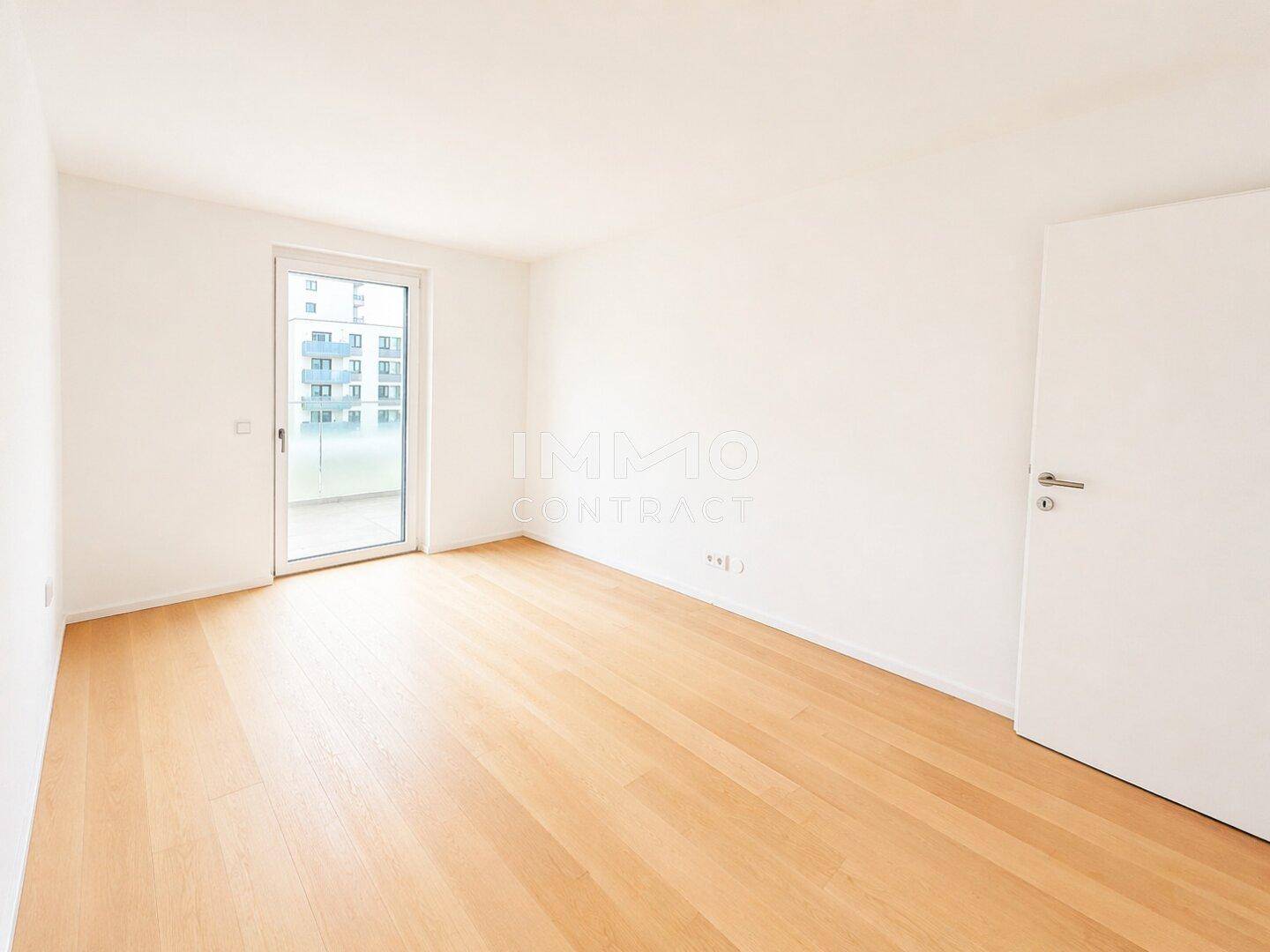 Helles Schlafzimmer mit Parkettboden und direktem Zugang zu einem Außenbereich.