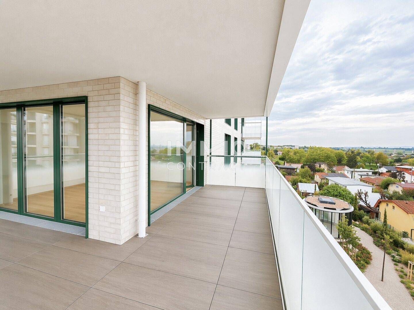 Geräumiger Balkon mit Fliesenboden und Glasbrüstung, bietet weite Aussicht über die Umgebung.