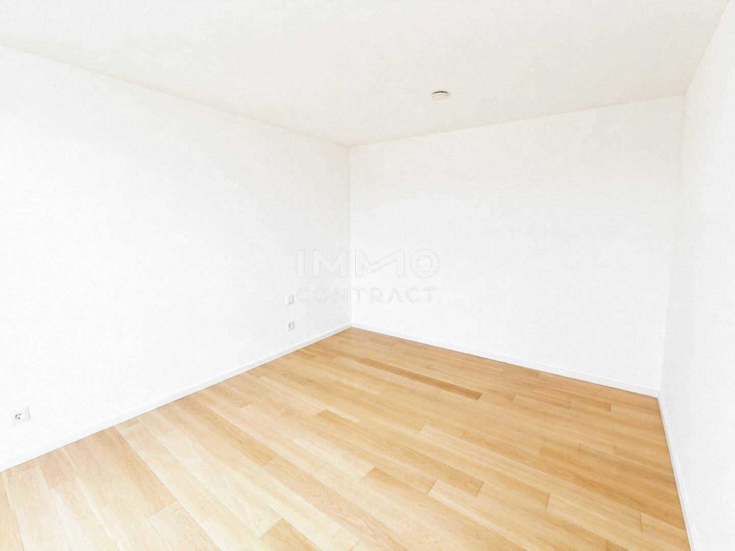 Leeres Zimmer mit hellen Wänden und Parkettboden, bereit zur individuellen Gestaltung.