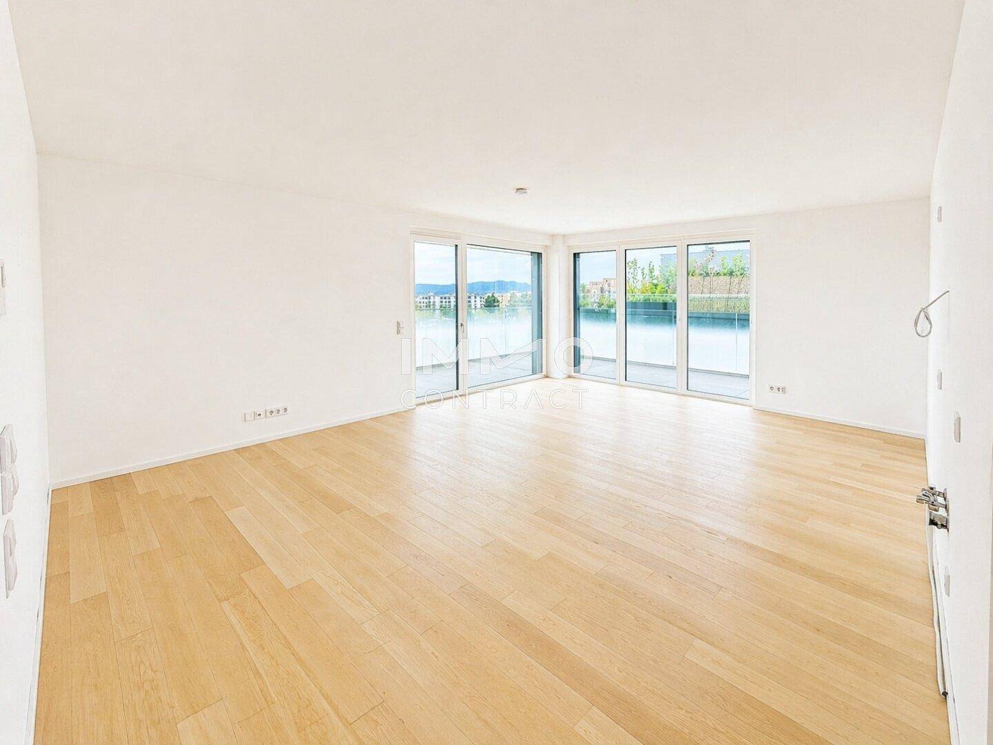 Heller Wohnbereich mit Holzparkett und großen Fenstern, die einen weiten Blick bieten.