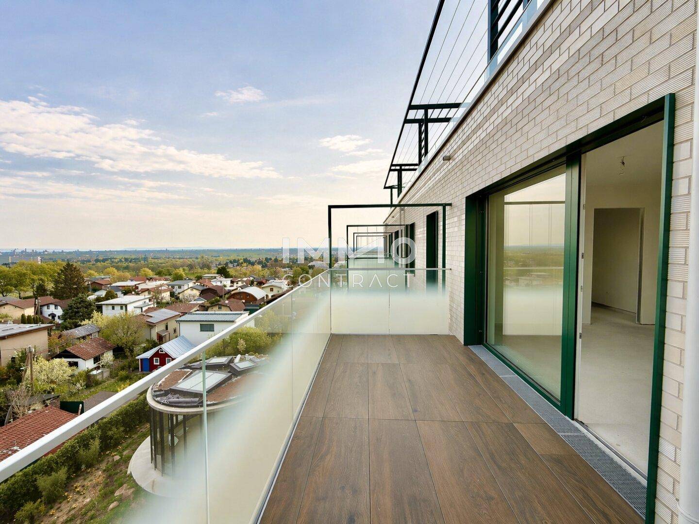 Geräumiger Balkon mit Glasbrüstung und weitem Blick über die umliegende Wohngegend.