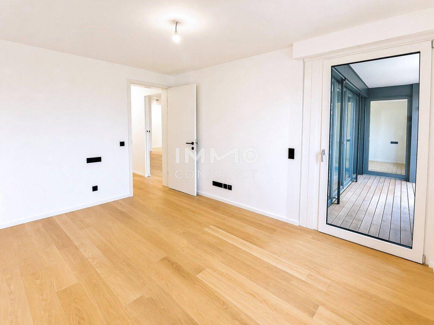 Heller Raum mit Parkettboden und Zugang zu einem Balkon, ideal als Schlaf- oder Wohnzimmer.