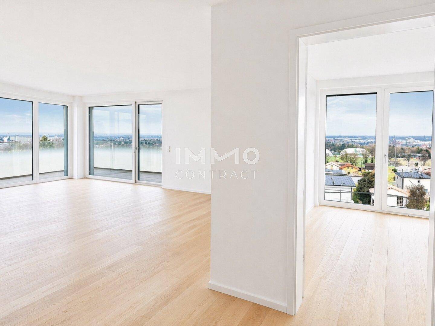 Geräumiger, heller Innenraum mit Holzboden und weitem Blick über die Stadt durch große Fenster.